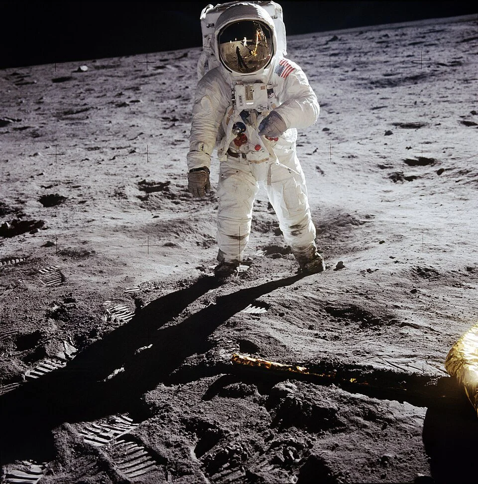 El astronauta Buzz Aldrin en la superficie lunar durante la misión Apollo 11, con Neil Armstrong y el módulo Eagle reflejados en su visor.