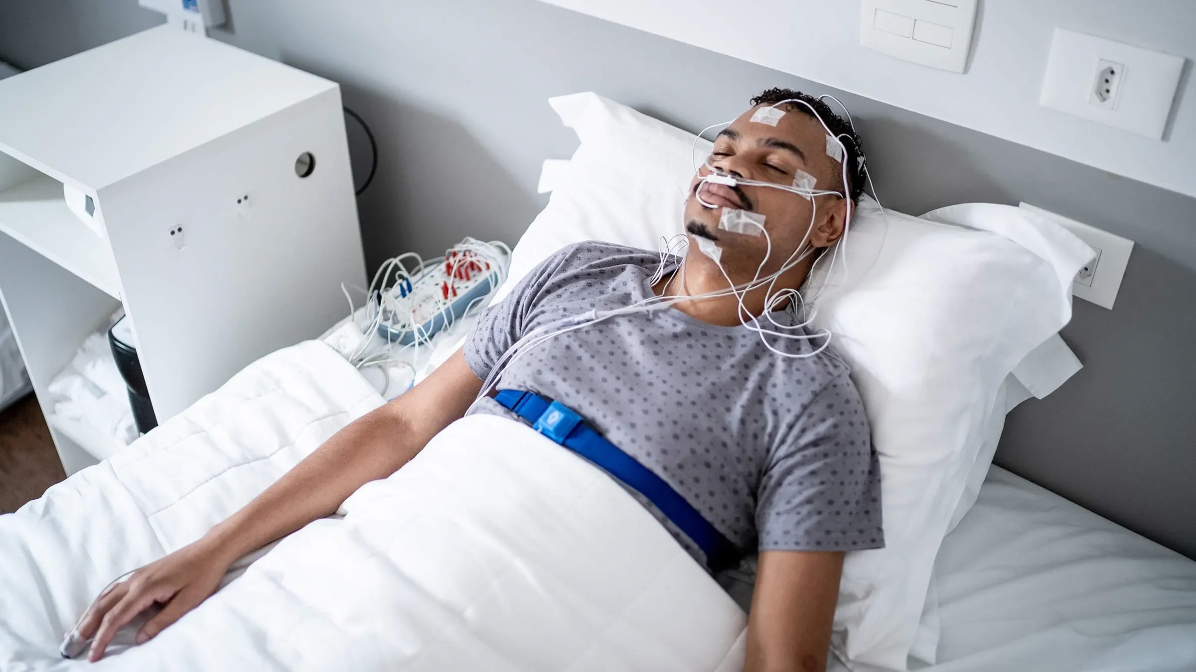 Participante de un estudio del sueño monitorizado mediante polisomnografía, una técnica que registra la actividad cerebral, la respiración, el ritmo cardíaco y otros parámetros fisiológicos durante el descanso.
