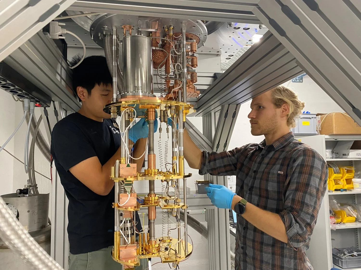 Jesse Zhang, a la izquierda, y Paul Wegmann completan el cableado de los detectores instalados en el refrigerador de dilución utilizado para enfriar el experimento cerca del cero absoluto.