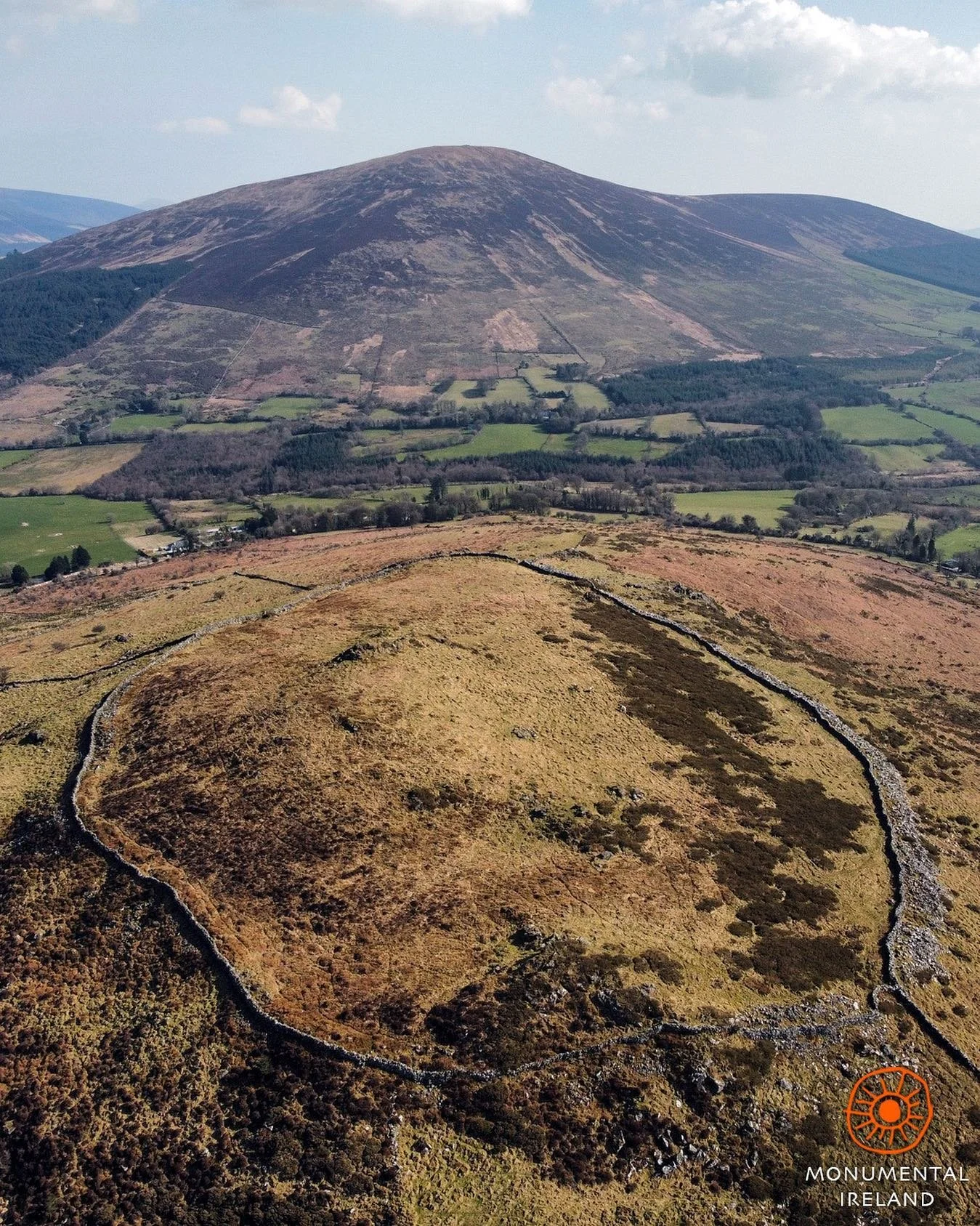 El recinto fortificado de Brusselstown, en el condado de Wicklow: parte del mayor complejo de castros de Europa, construido en la Edad del Bronce medio hacia 1500 a. C. Al fondo, se alza la silueta imponente de la montaña Keadeen.