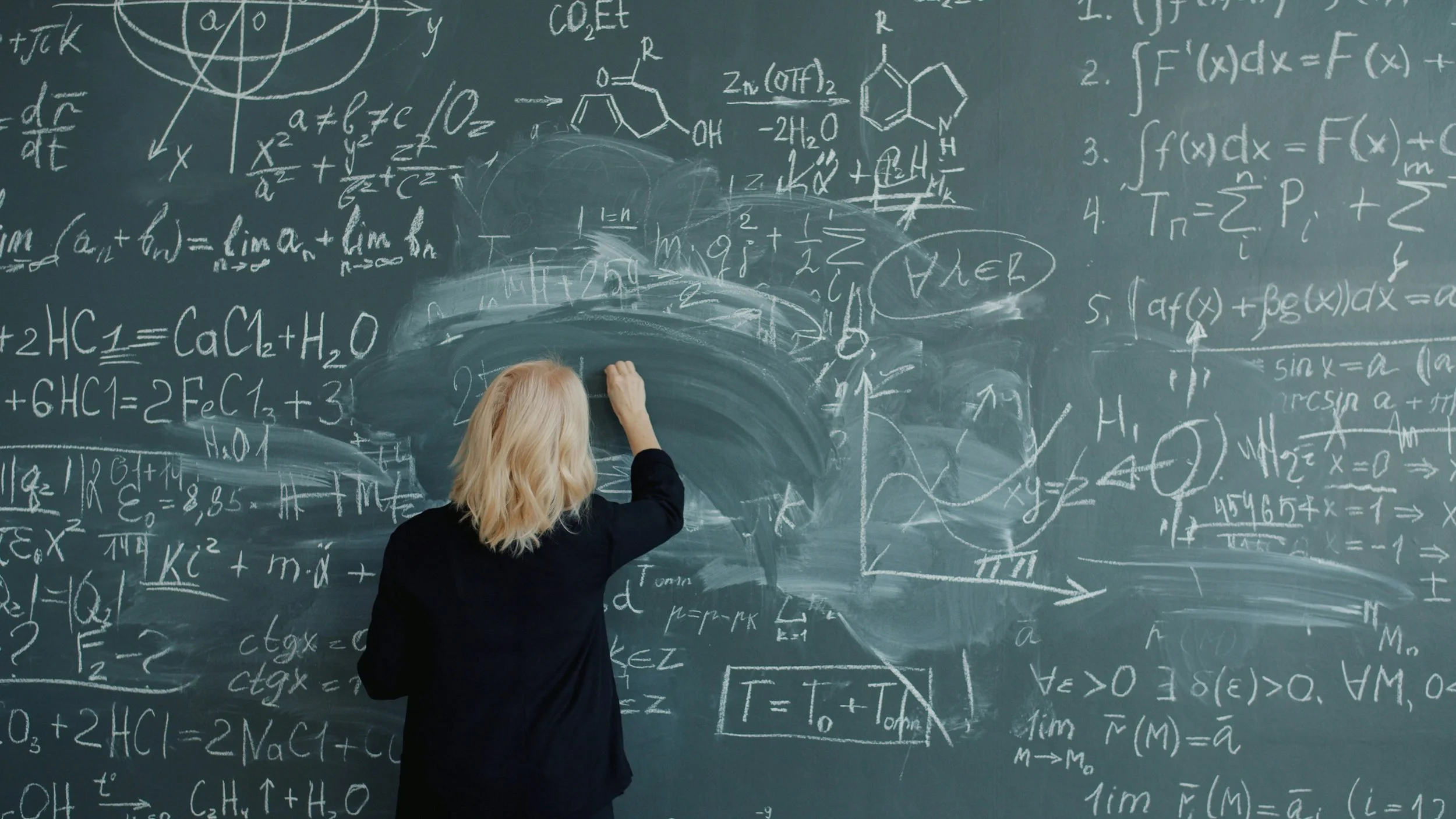 na profesora escribe en la pizarra: la preferencia por la mano derecha, presente en el 90% de la población, podría explicarse por dos hitos clave de la evolución humana, el bipedismo y el crecimiento del cerebro.