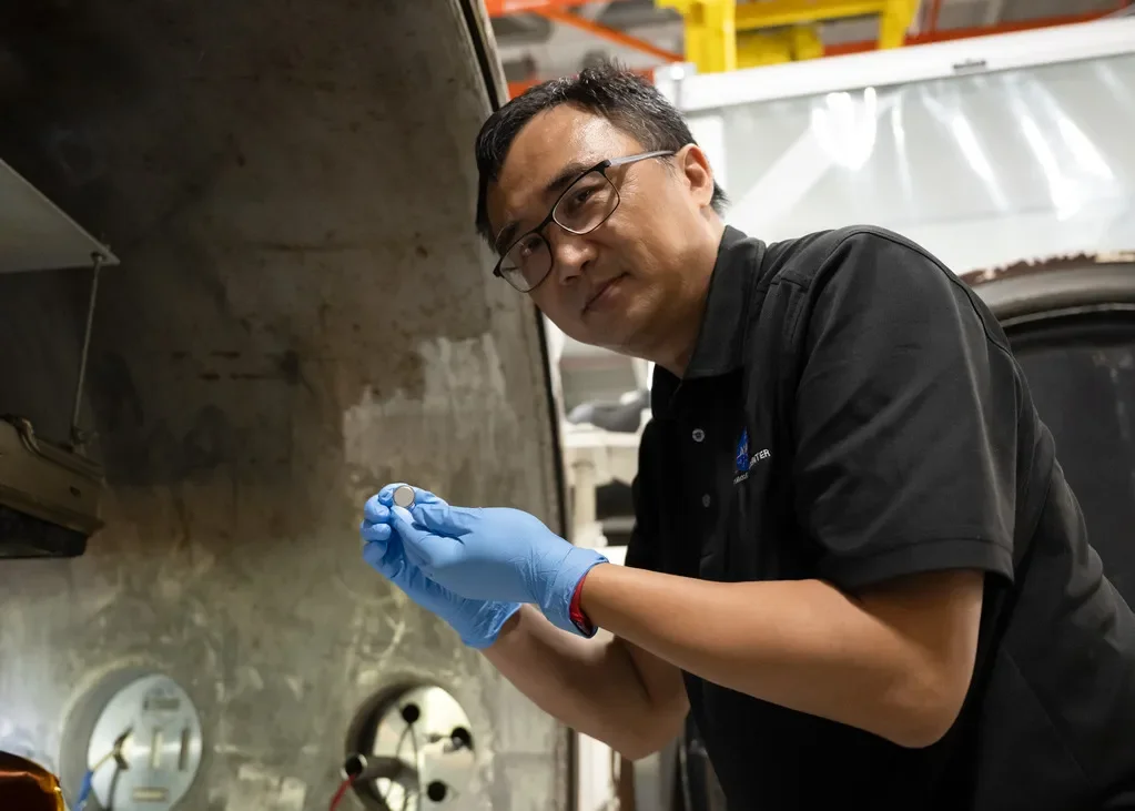 Yi Lin, responsable de investigación y ensayos de SPEARS en el centro Langley de la NASA, muestra una de las pequeñas baterías de botón tras las pruebas de vacío térmico.