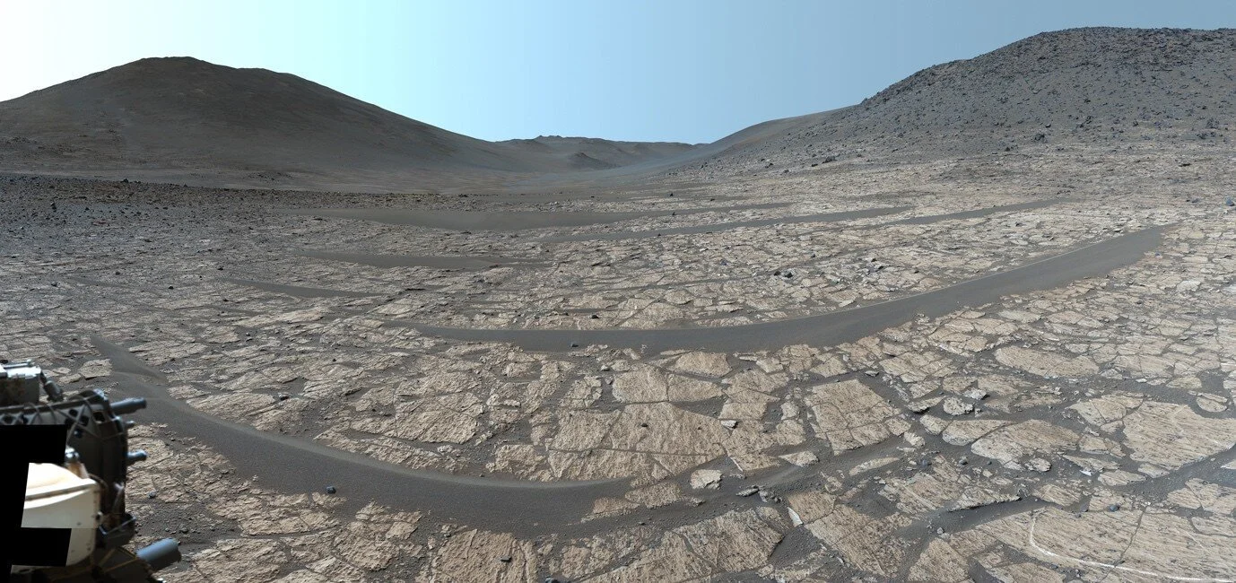 El róver Perseverance observa el valle Neretva Vallis, el antiguo cauce fluvial que alimentó el lago del cráter Jezero hace más de 3.500 millones de años; en primer plano, afloramientos claros de lutitas finas de la formación Bright Ange
