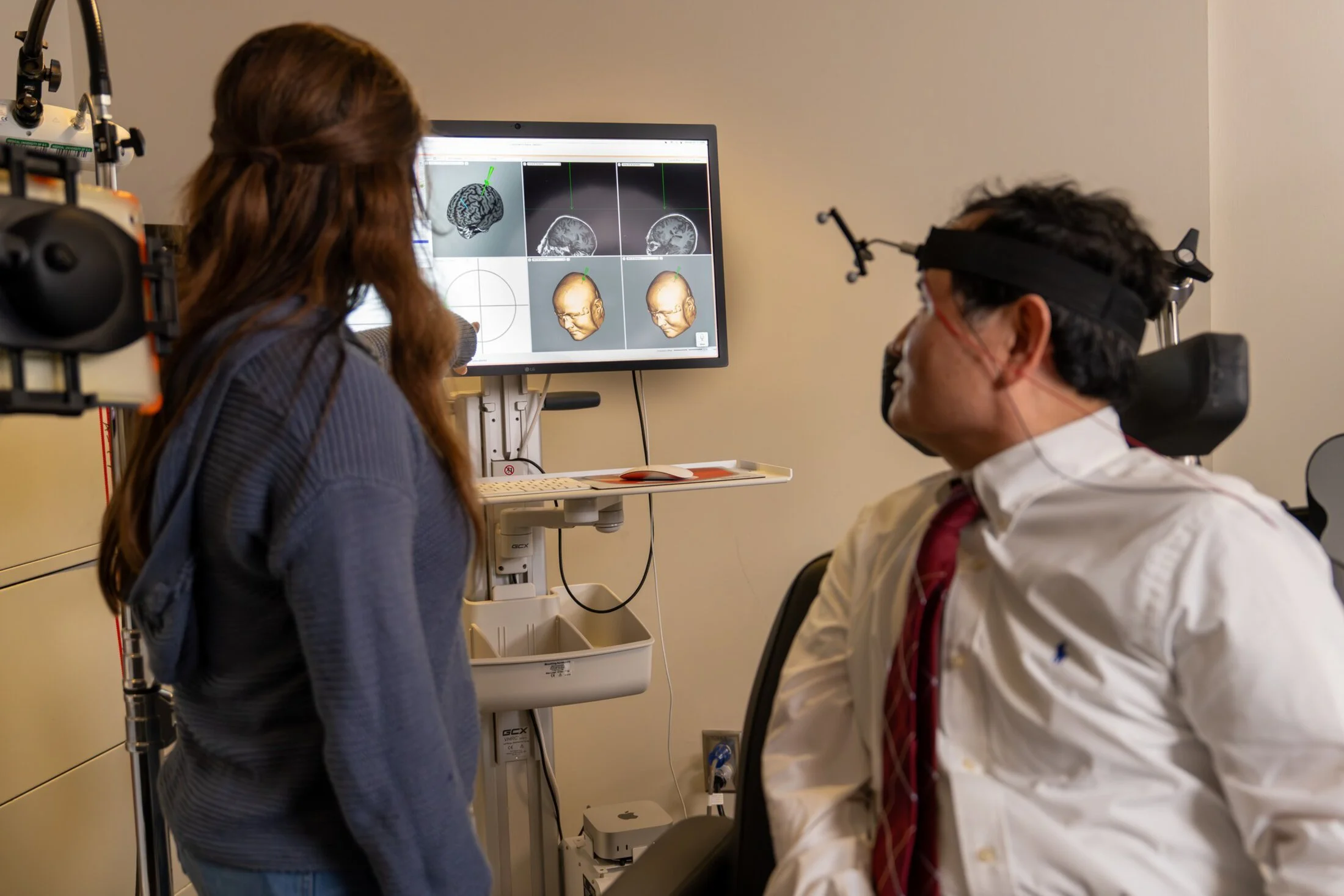 La investigadora Rebecca Keneally y el psiquiatra Xingbao Li observan las imágenes cerebrales durante una demostración de estimulación magnética transcraneal repetitiva (rTMS.