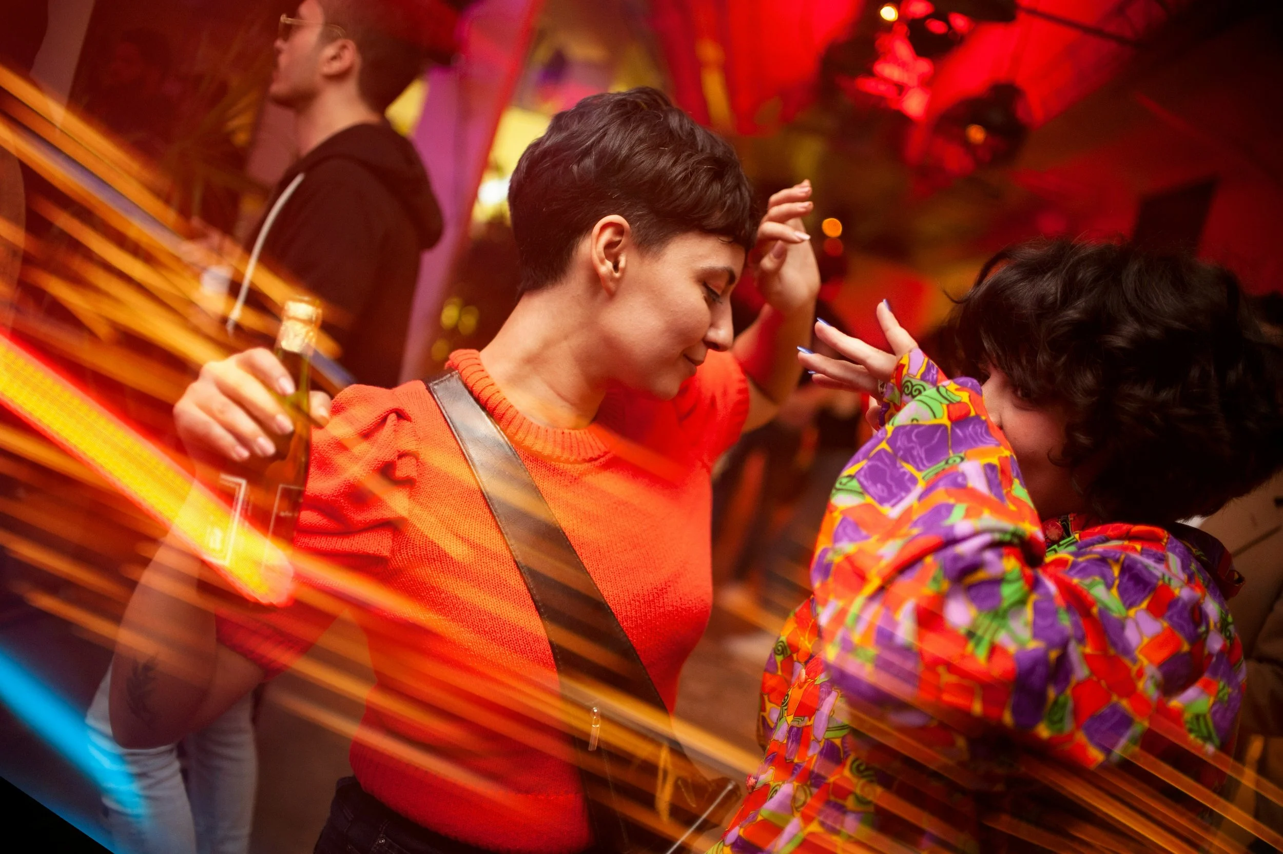 Dos mujeres bailan en sintonía en una discoteca: la coordinación de sus movimientos puede reflejar una sincronización cerebral que refuerza la conexión entre ambas.