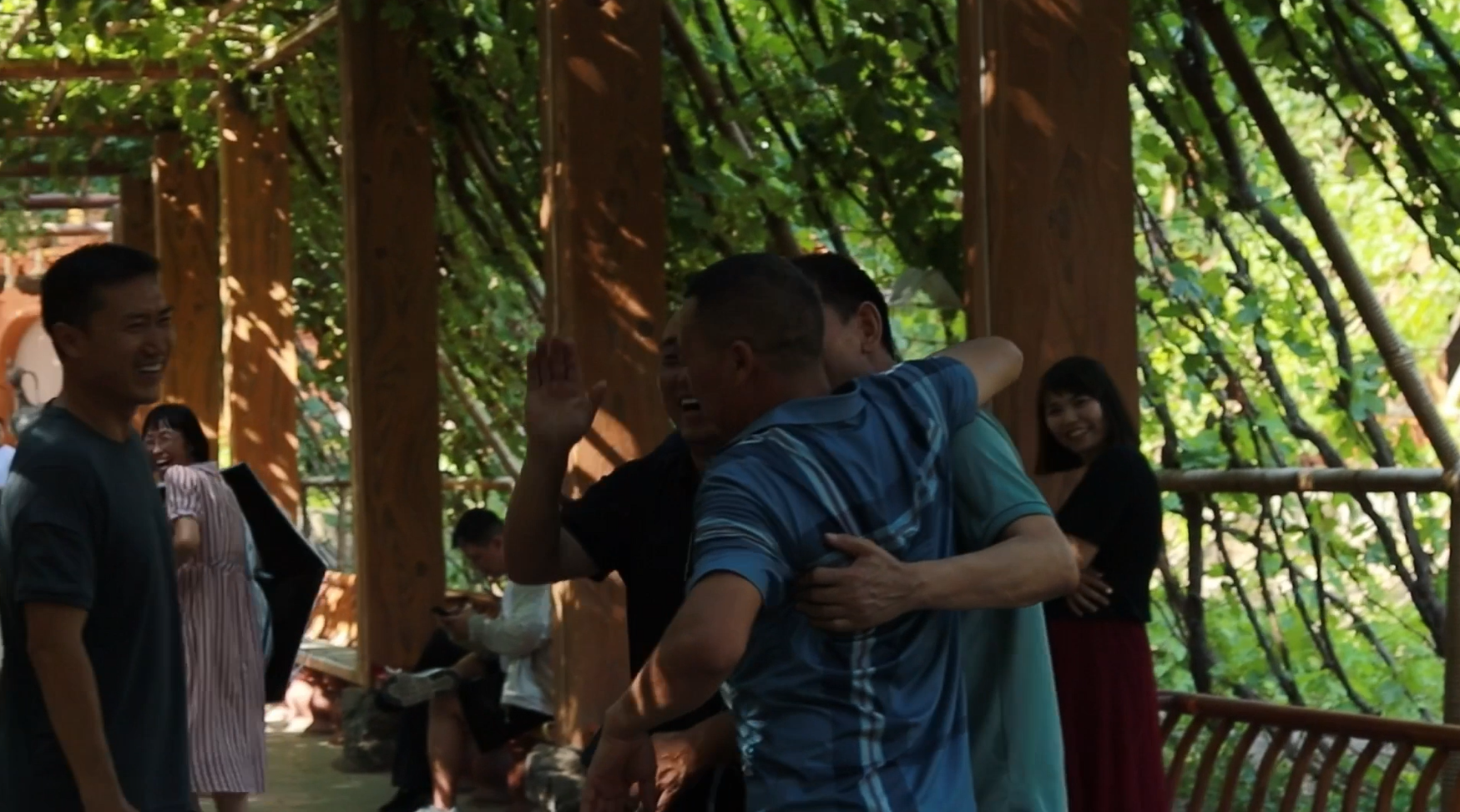 A group of locals in Turpan sharing laughter and dancing beneath a grape-covered pergola