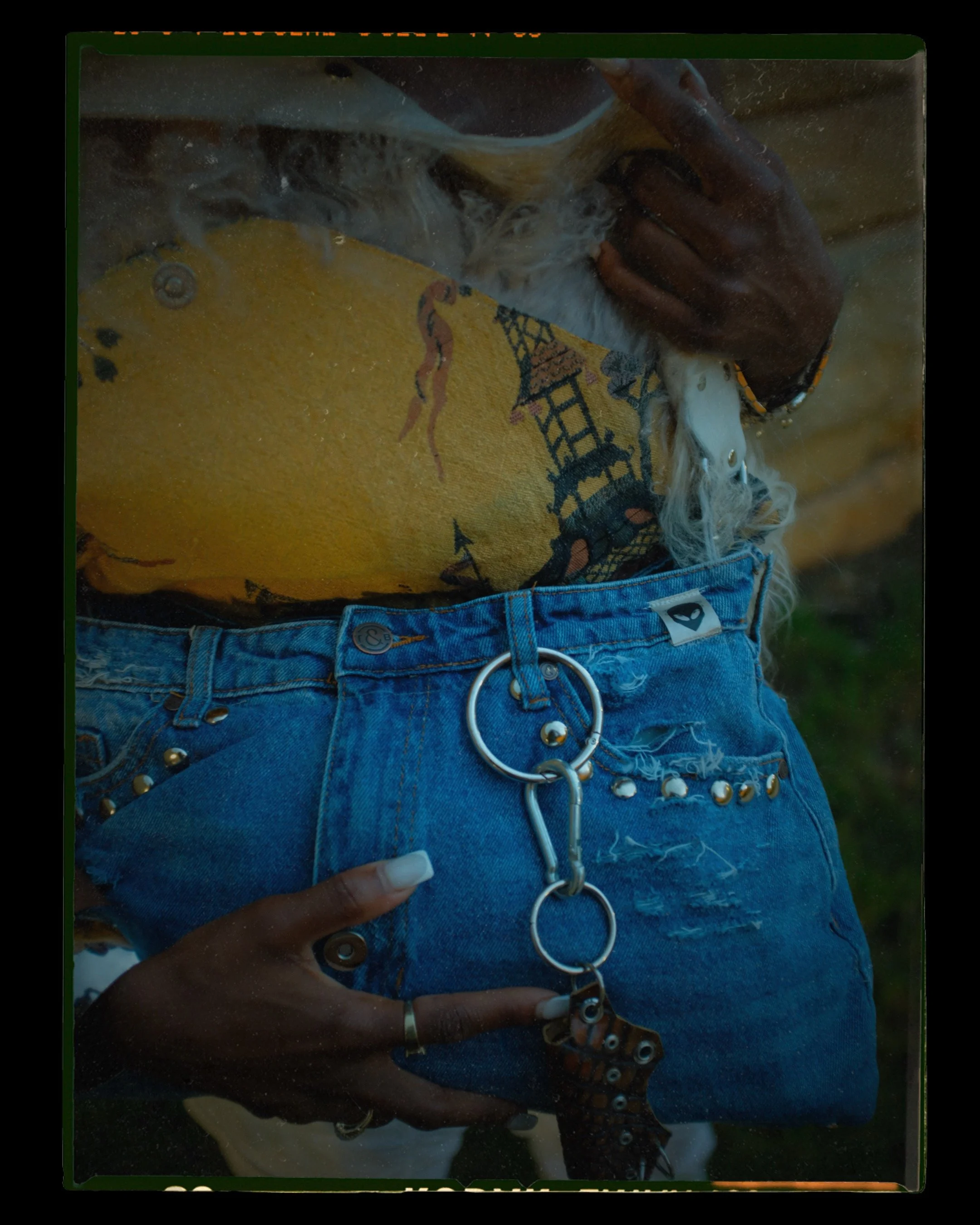 A person wearing a yellow shirt with a graphic design and denim shorts, holding a handmade luxury handbag with Mongolian sheep fur