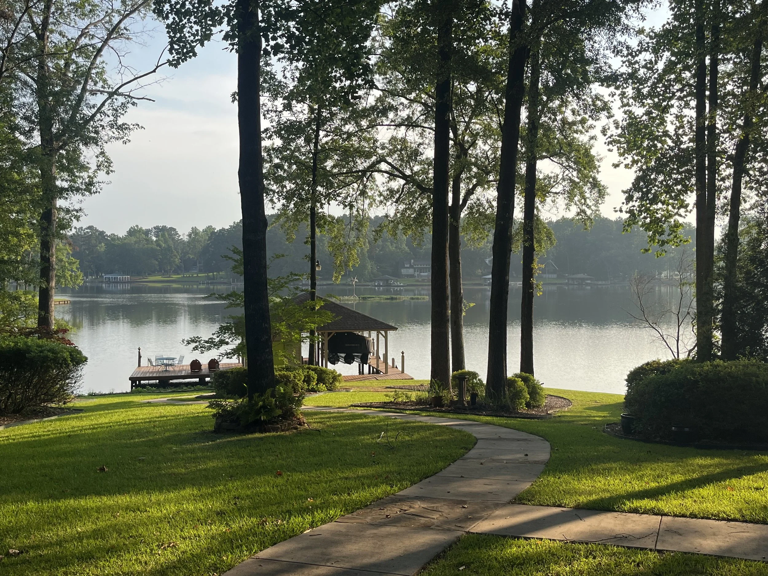 Lake view from downstairs porch with concrete walkway to dock.