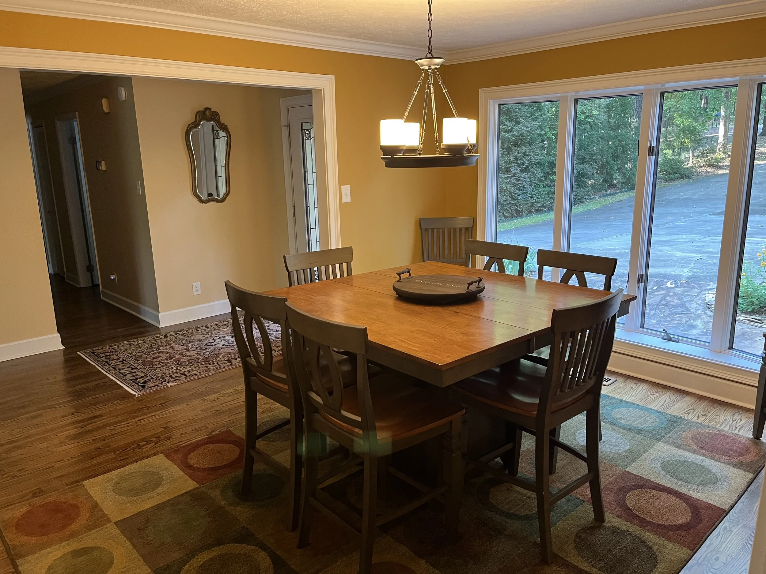 Dining room with dining table and eight chairs at front entrance with bay window overlooking front yard.