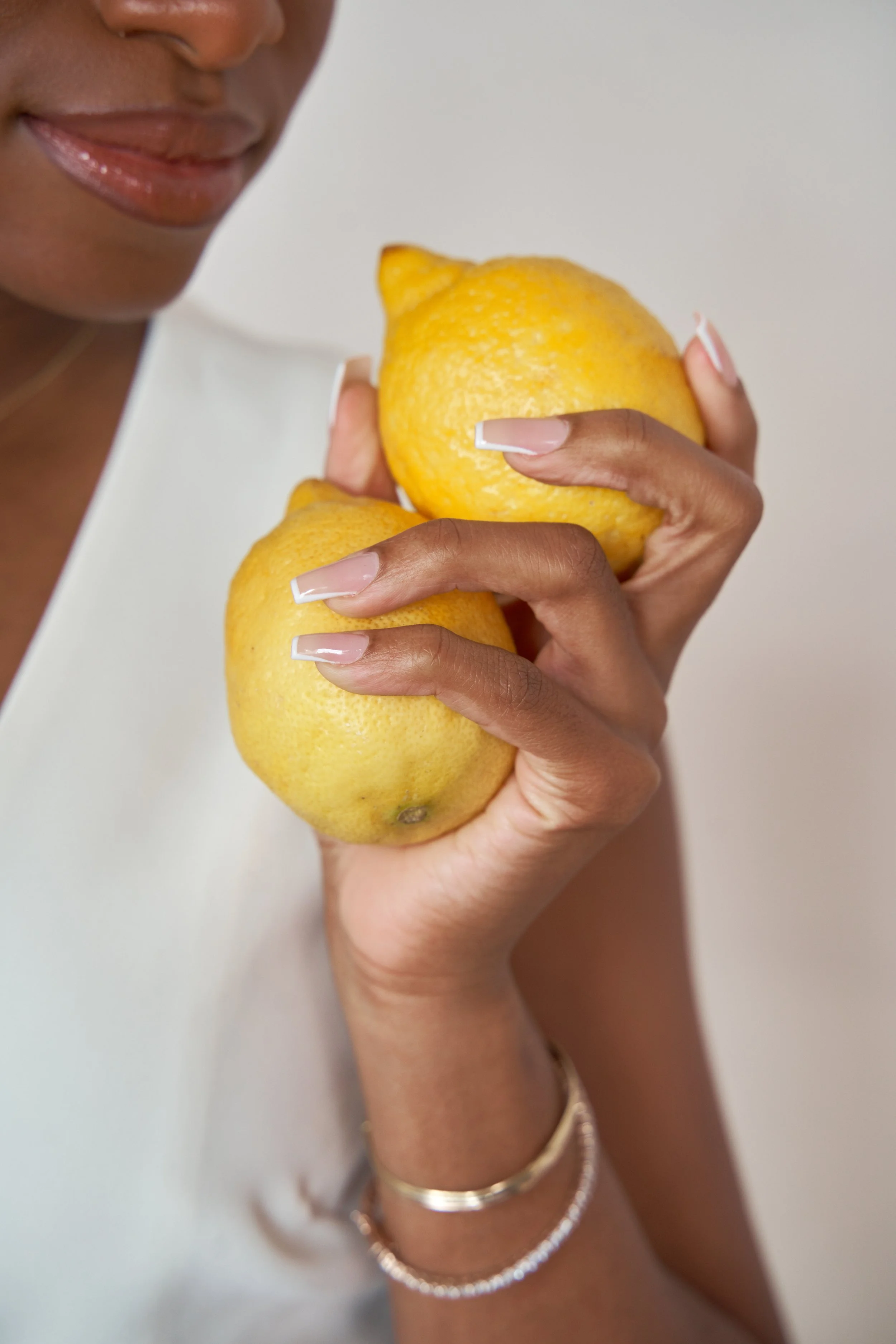 Person holding two large yellow lemons.