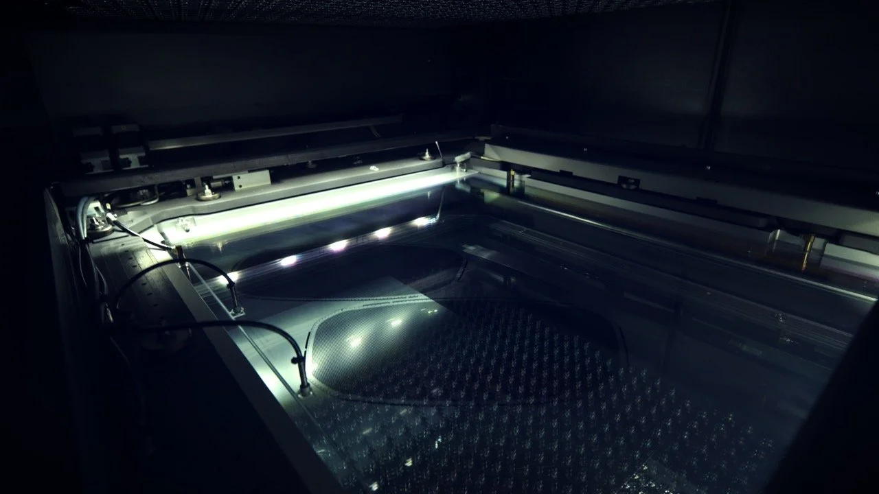 A close-up view of a laser engraving or cutting machine with internal components visible, illuminated by a bright light.