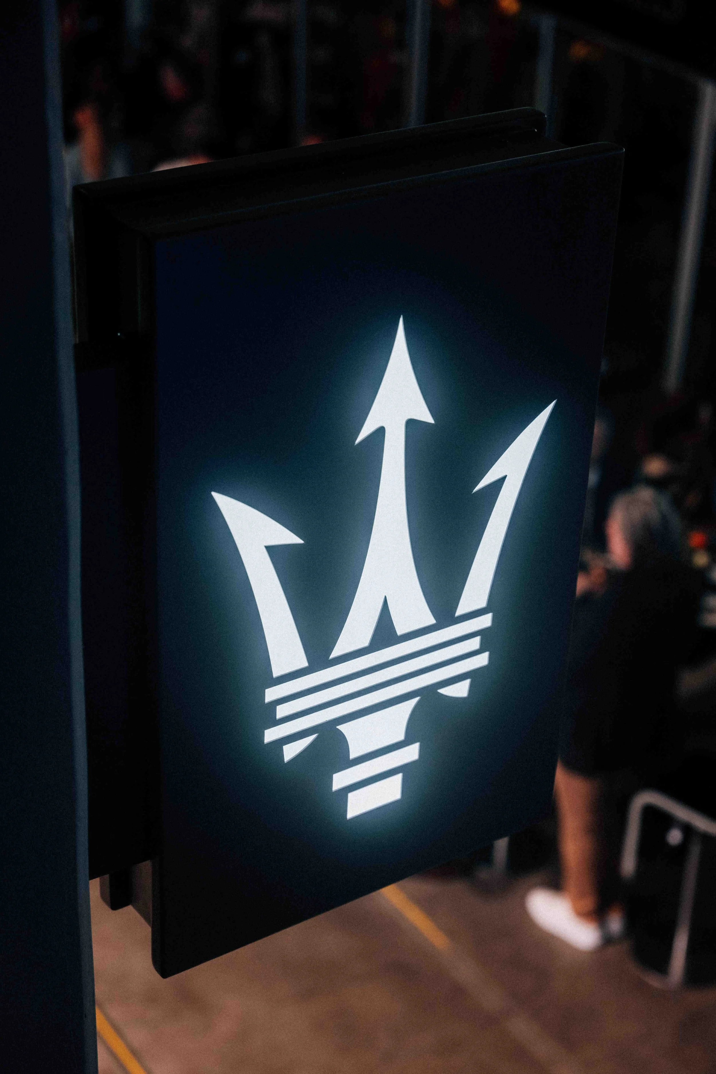 Backlit sign with a stylized trident logo.