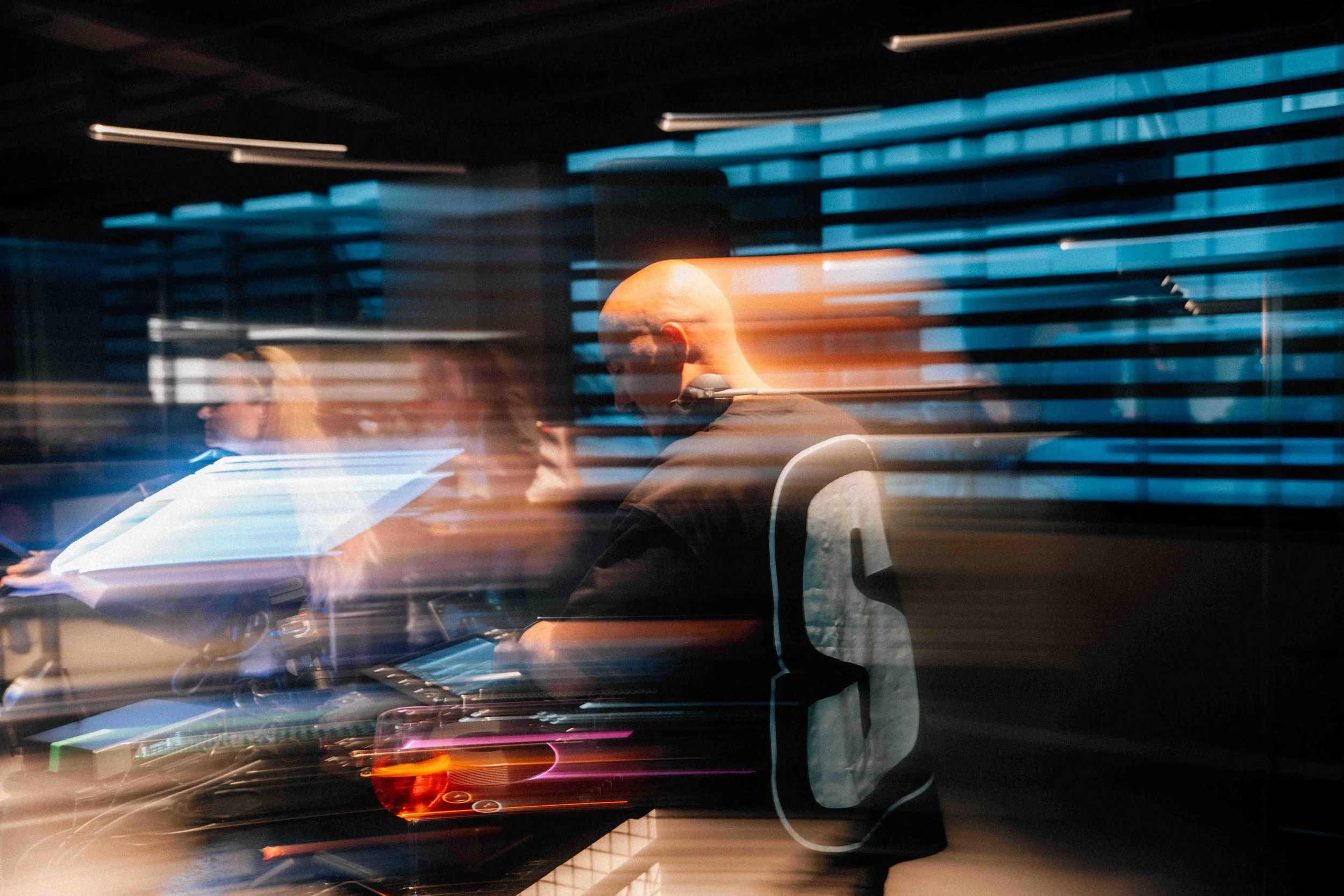 A person with a shaved head working on a computer at a desk with streaks of light creating a motion blur effect.