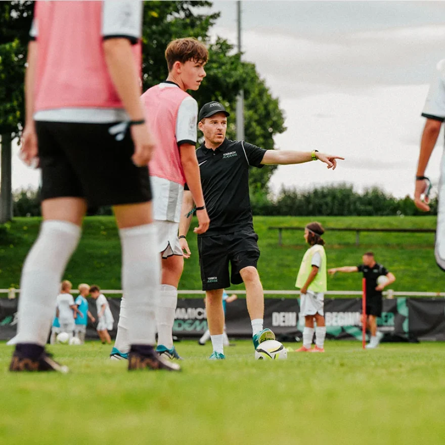 Soccer coach giving instructions to young players during practice on a soccer field.