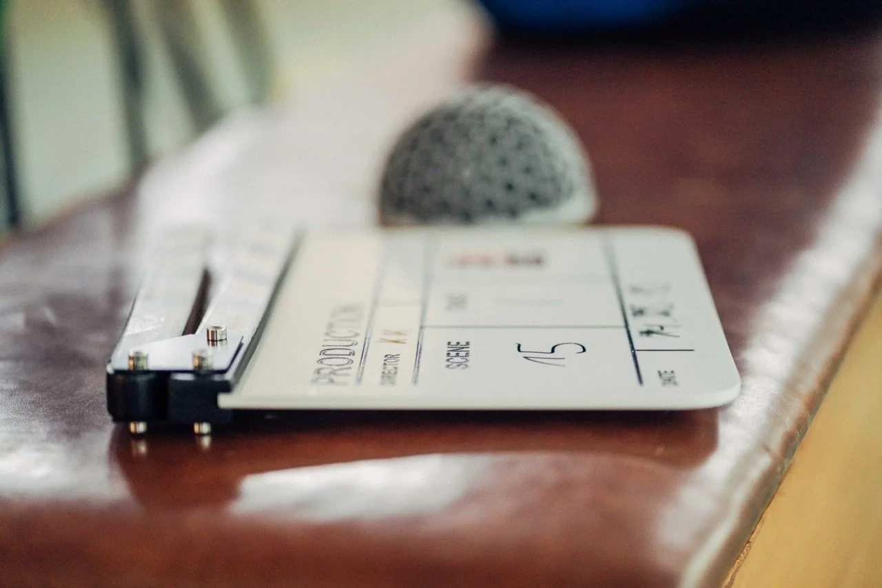 Close-up of a boarding pass on a wooden surface, with a small gray stone and a pen in the background.
