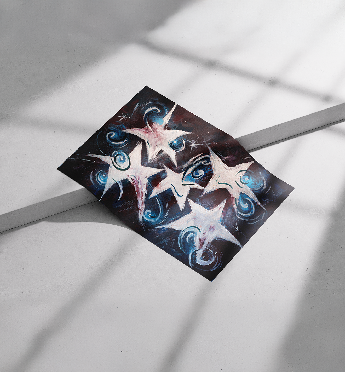 A colorful painting of multiple white stars with swirling blue and pink accents on a black background, lying on a white surface with shadows cast nearby.