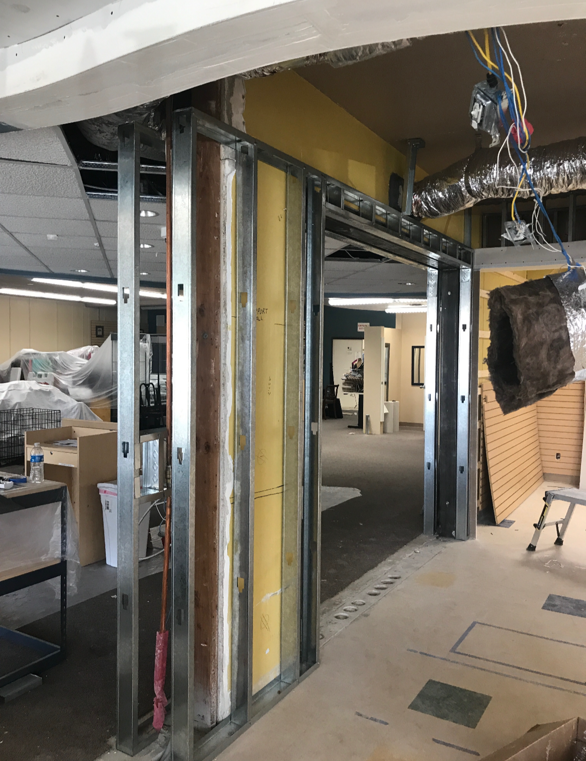 Interior of a building under construction with metal framing for a new wall and visible ductwork.