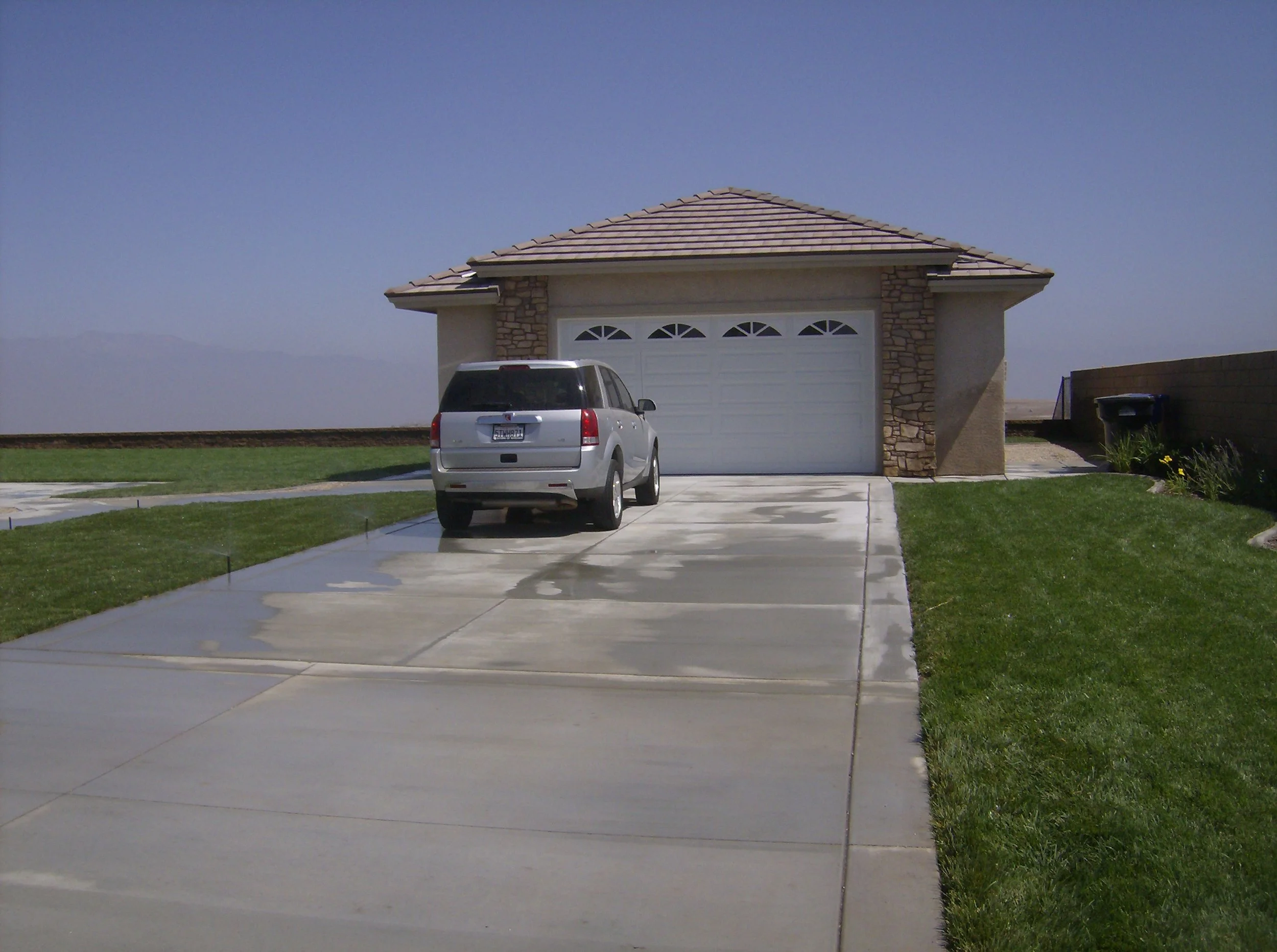 A suburban house in Riverside with a garage, a driveway with a parked SUV, and a lawn on either side under a clear sky.