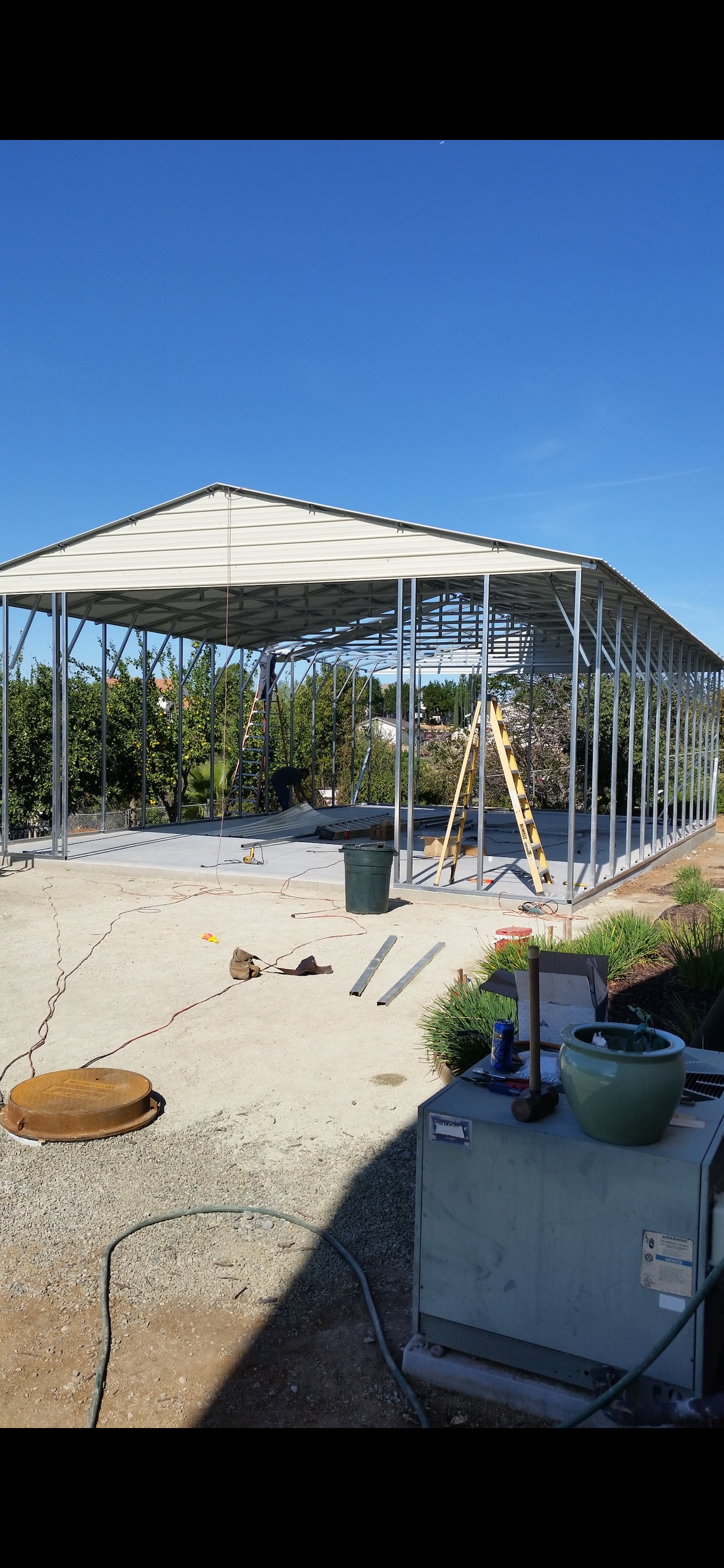 Construction of a metal-framed building under a clear blue sky.