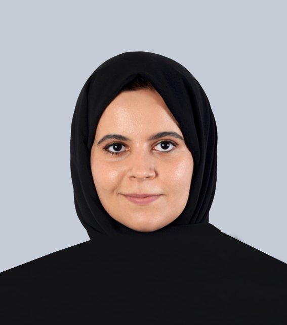 A woman wearing a black hijab against a gray background.