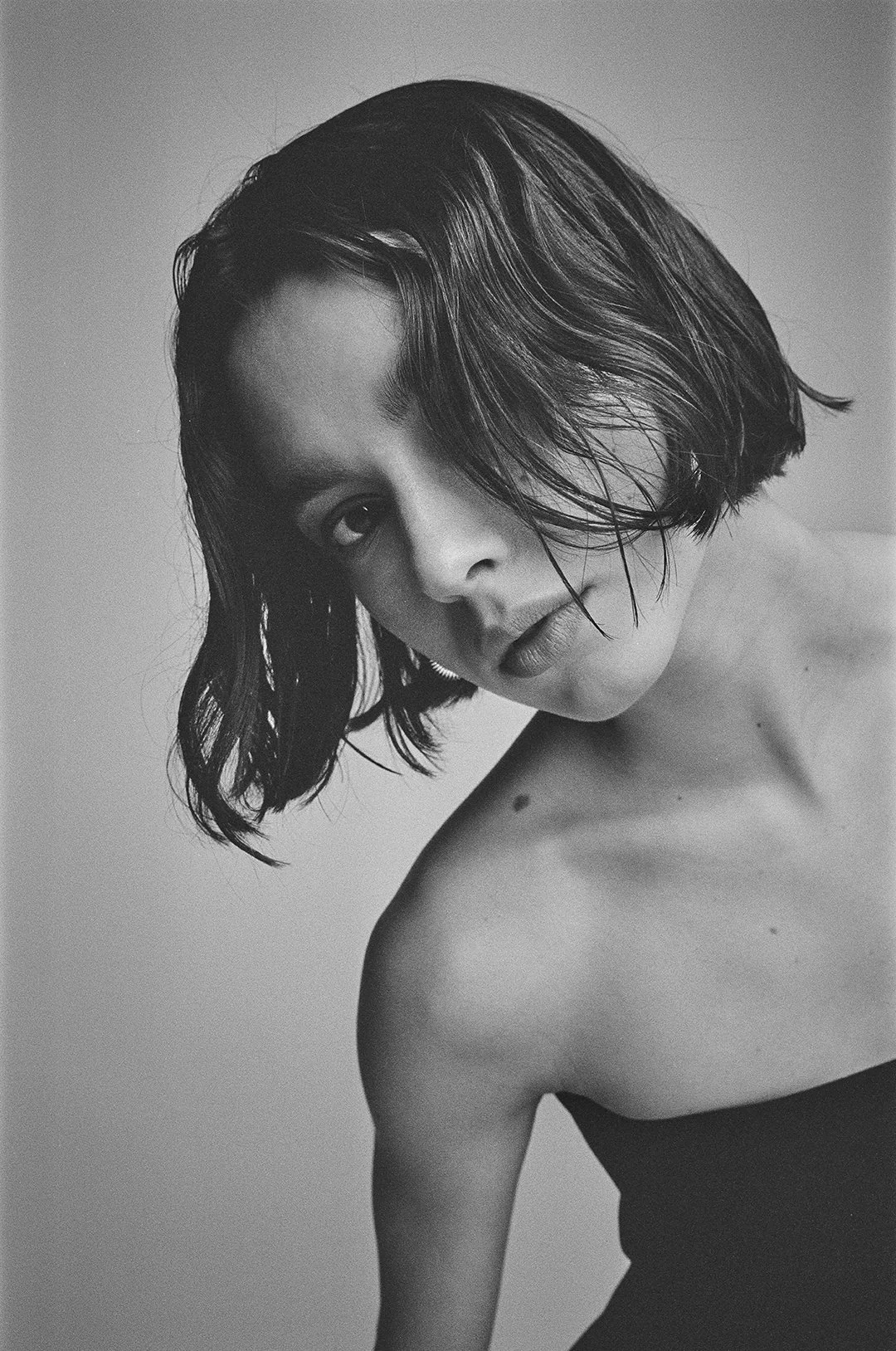 Black and white portrait of a woman with short, wavy hair, looking directly at the camera with an intense expression.
