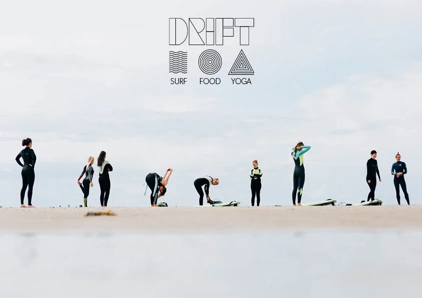 Group of people on a beach practicing yoga with surfboards nearby, under a cloudy sky, with text "DRIFT" and icons representing surf, food, and yoga.