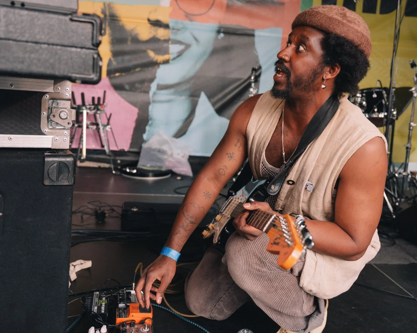 man crouching down on stage holding a guitar and adusting an effects pedal at manchester jazz festival 2026