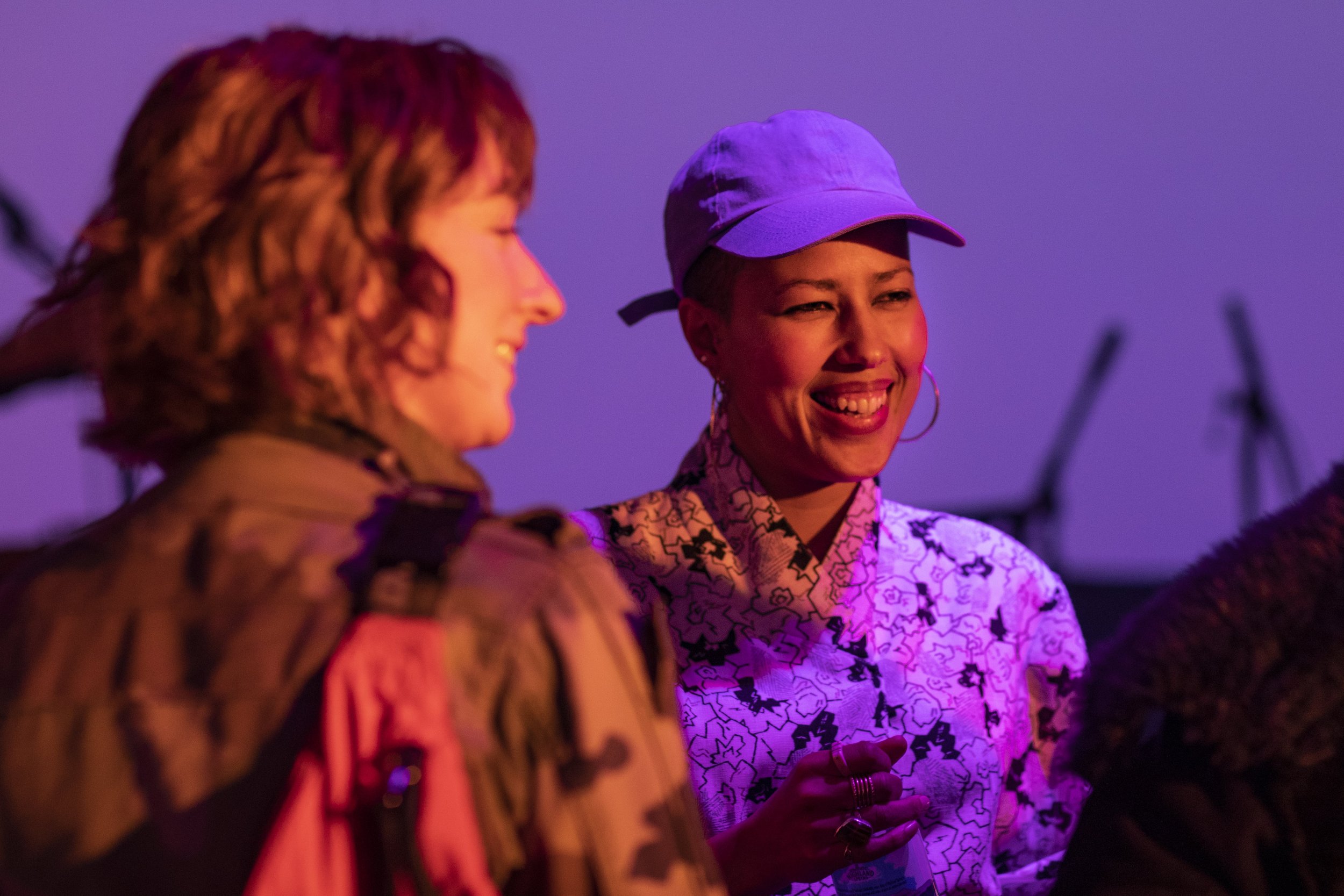 two musicians smiling and taking in front of a purple background