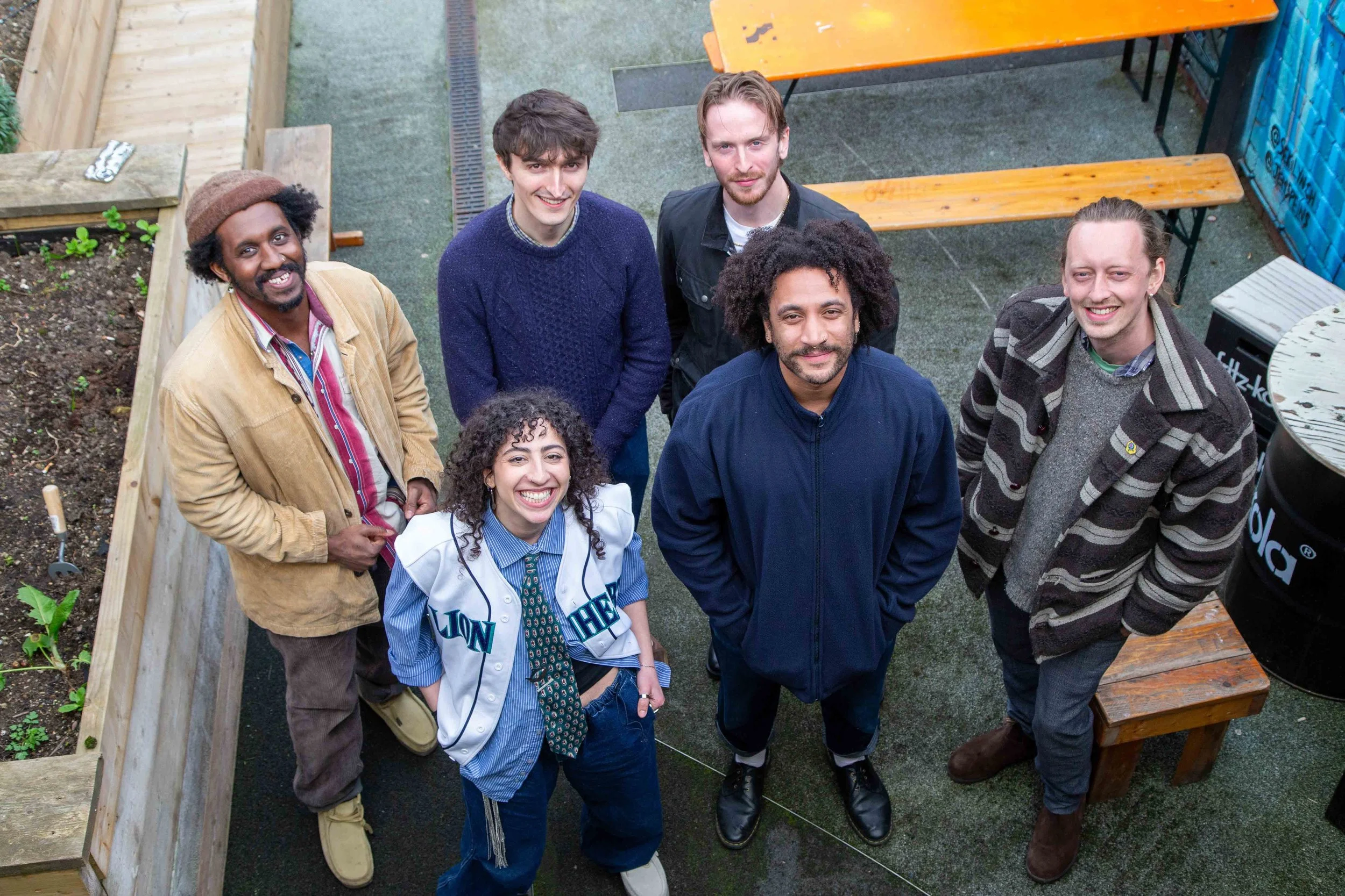 six musicians smiling and looking up at the camera