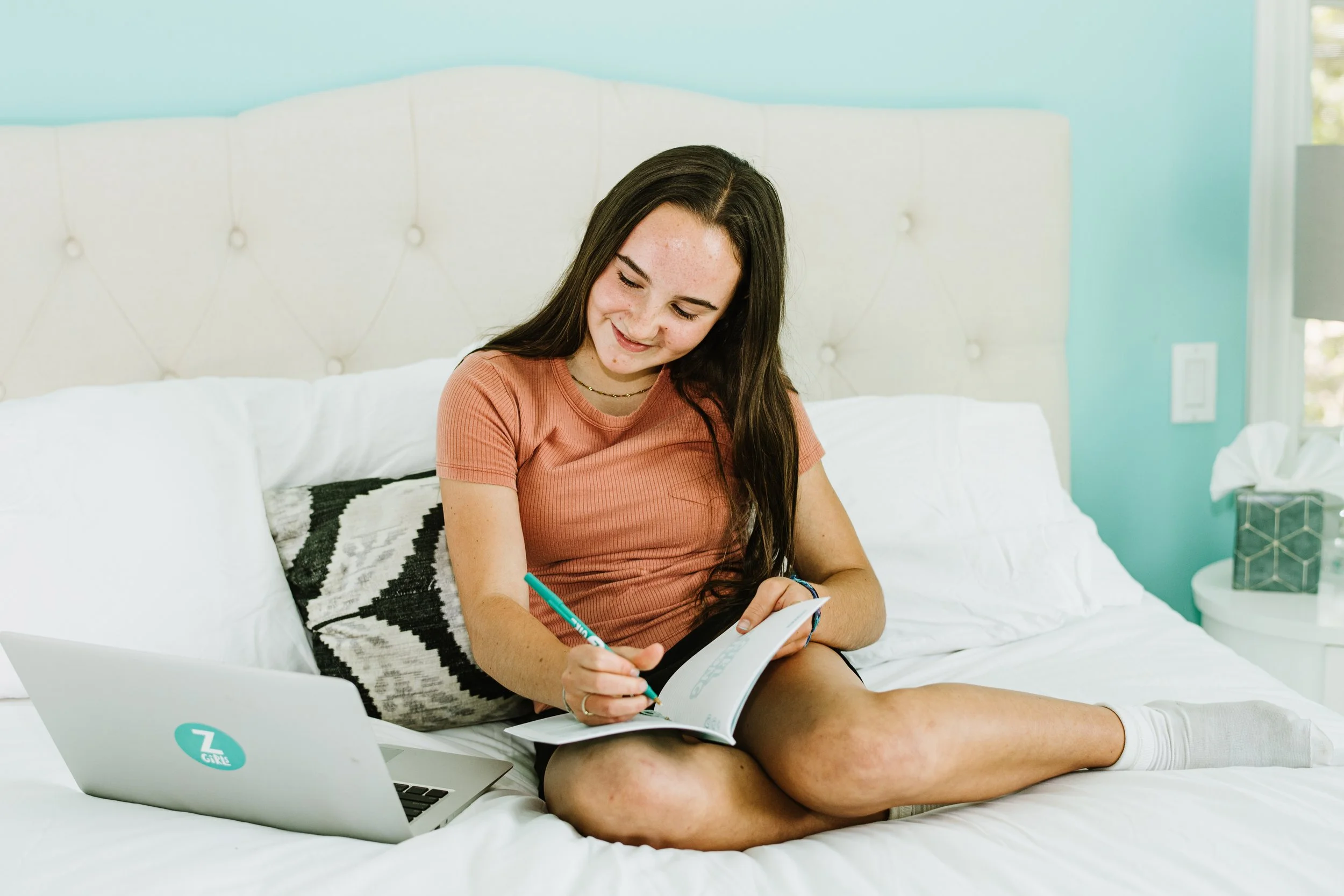 ZGiRL sits by her computer while writing in her Mindset Journal.