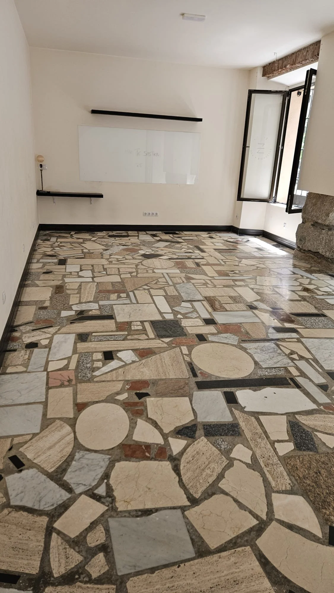 Interior view of a premium, minimalist yoga studio space in Madrid Centro near Ópera, featuring original flooring available for space hire and workshops.