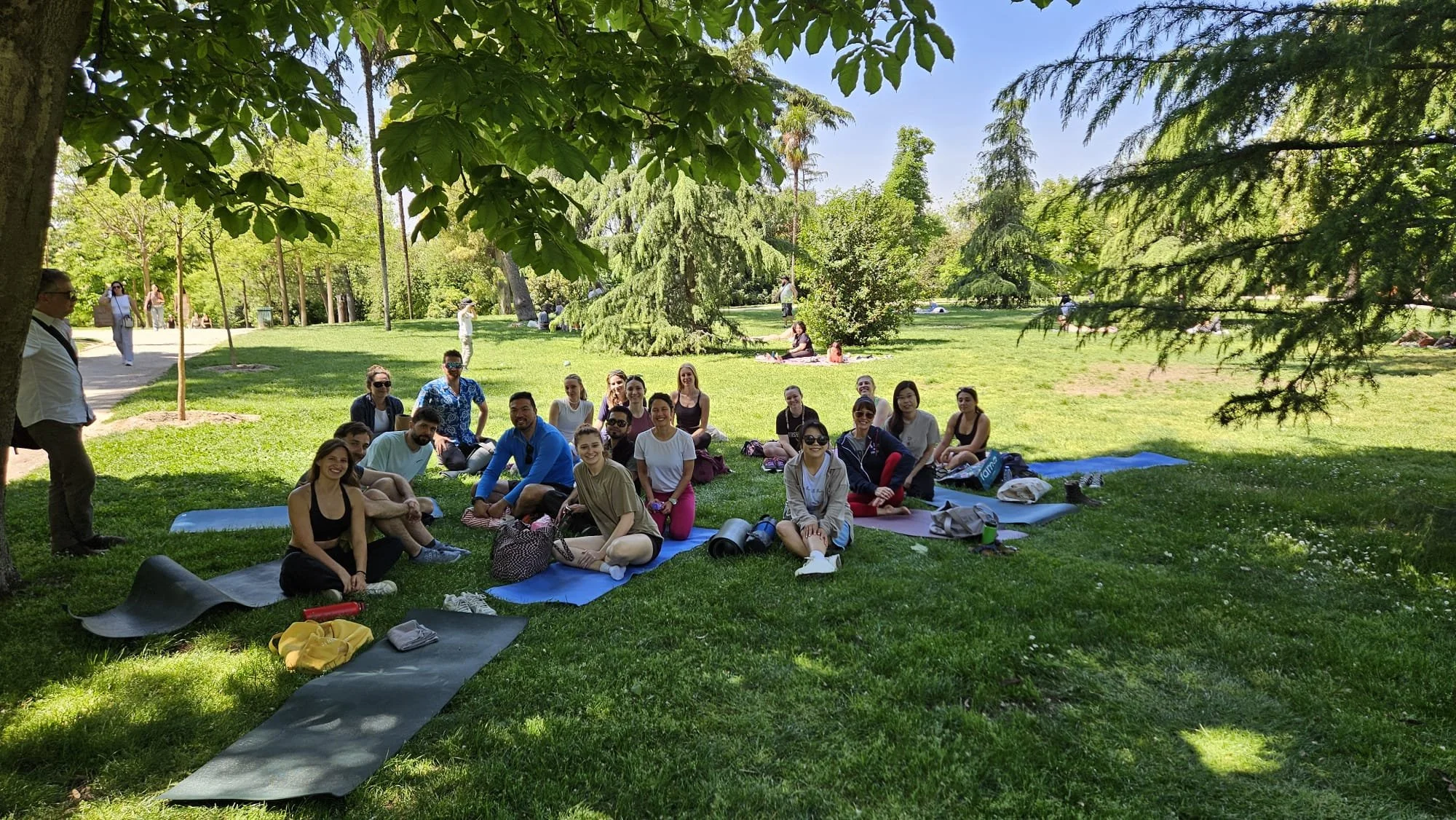 people gathered on yoga mats in a park looking happy at the camera