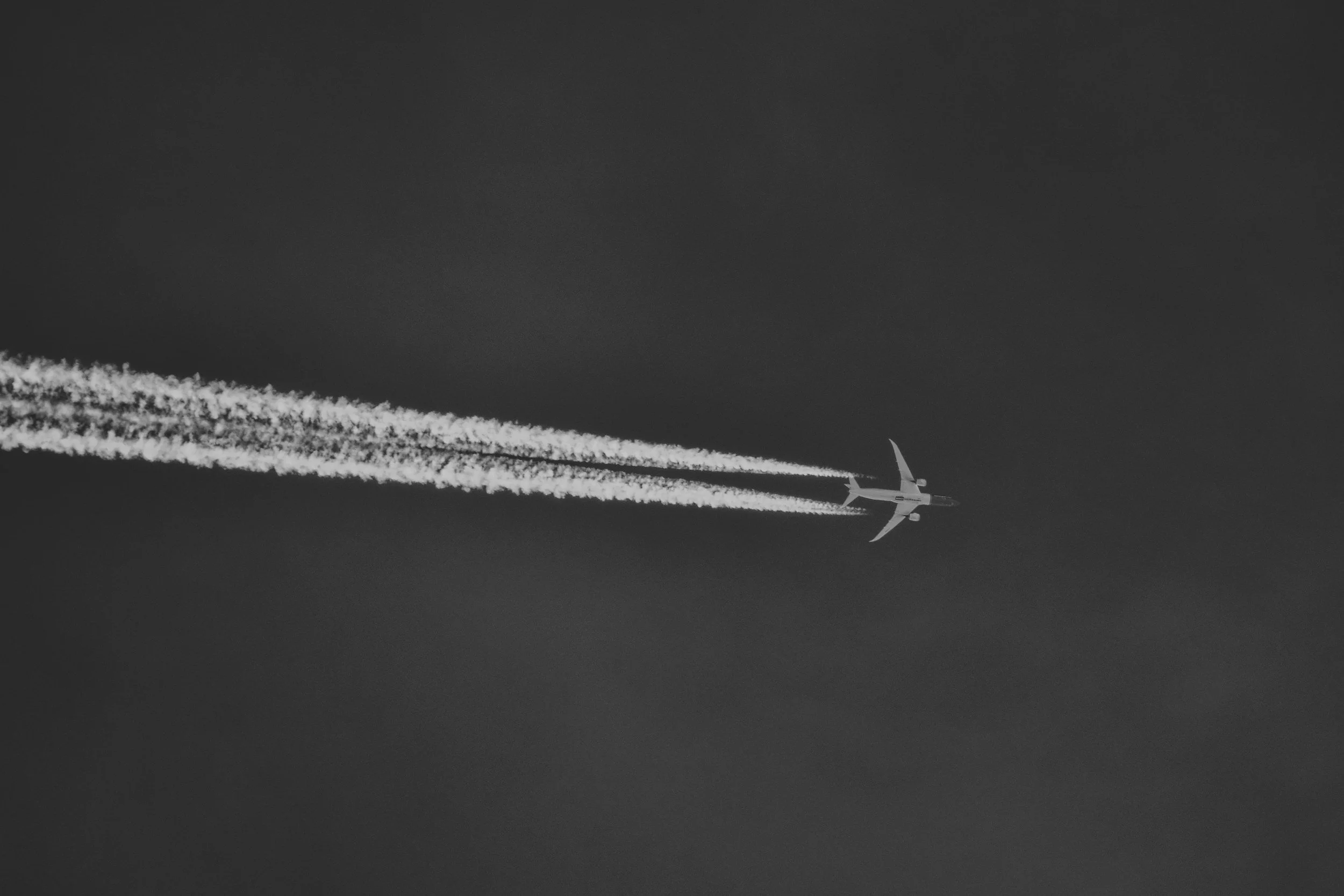 Plane in dark sky with long, white contrails