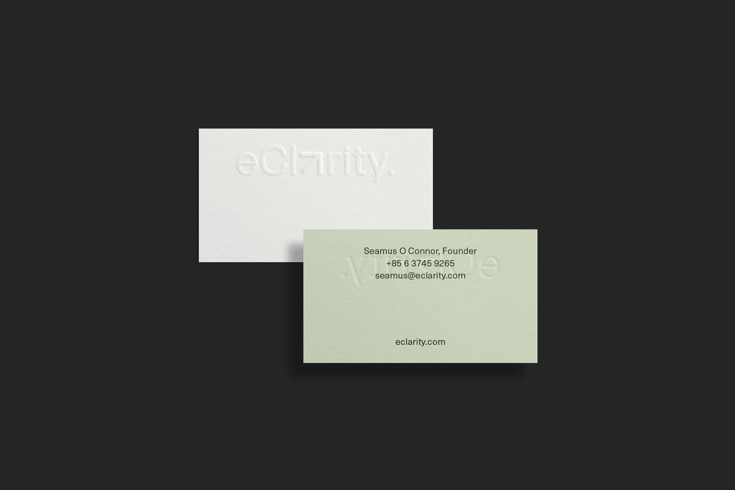 Two embossed business cards, one white and one light green, on a dark background. The white card has an embossed logo that reads 'eClarity,' and the green card provides contact information for Seamus O Connor, including email and phone number.