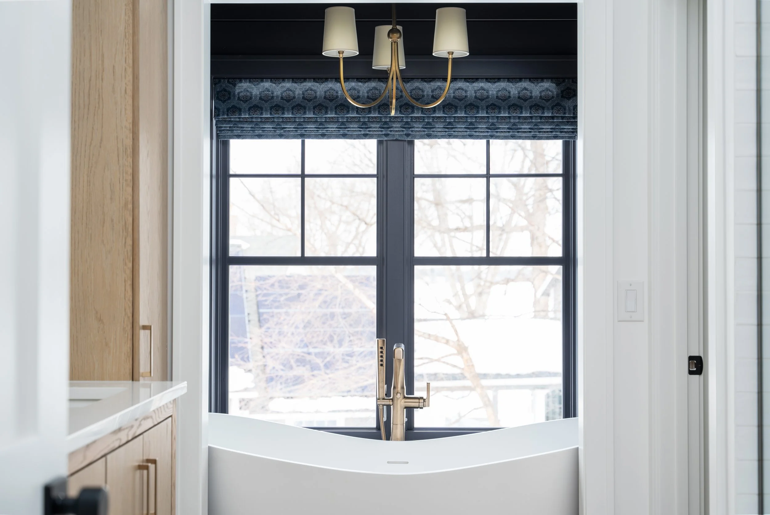 Bathroom with chandelier above tub, and Roman shades