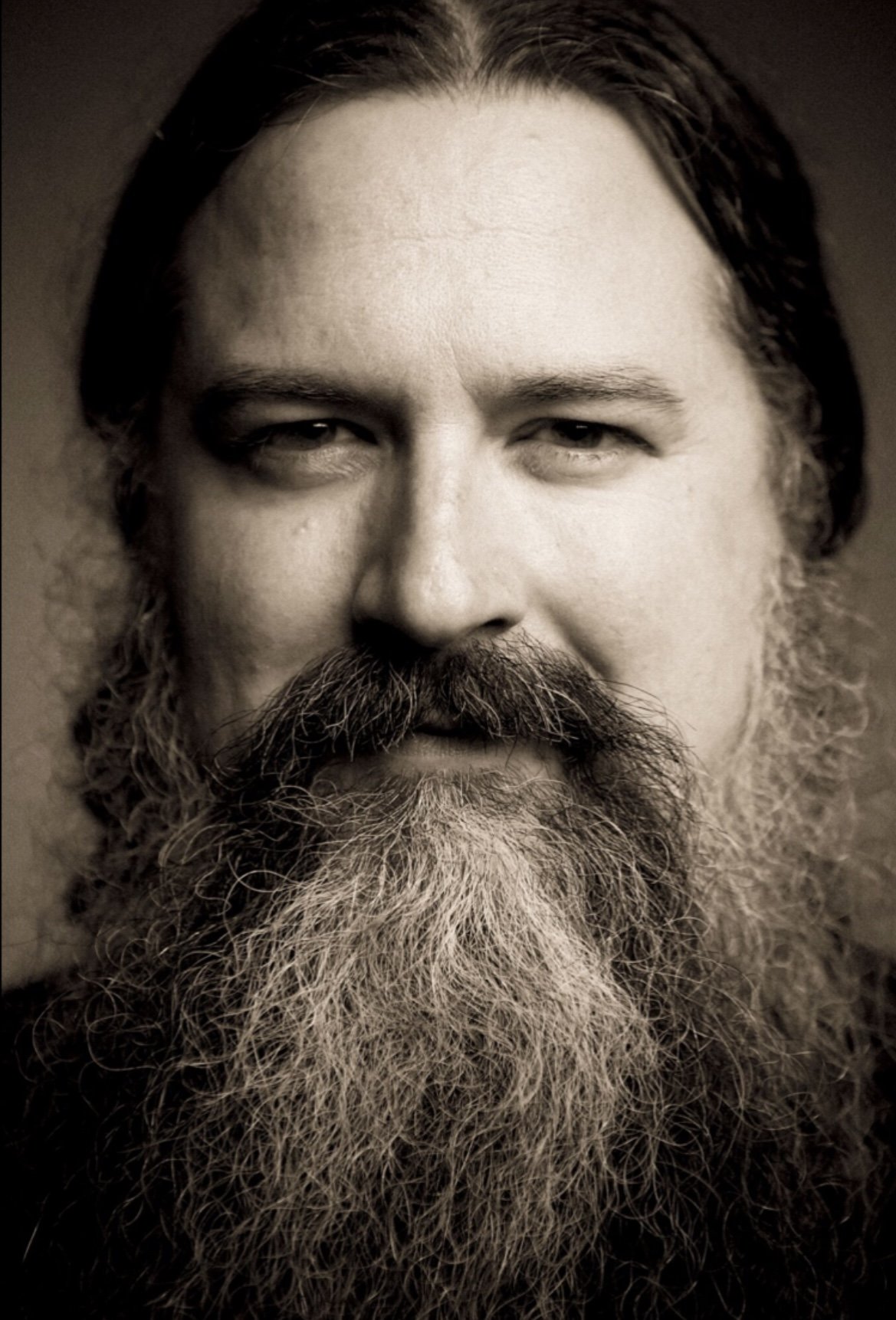 Black and white close-up portrait of a man with long hair and a large, full beard.
