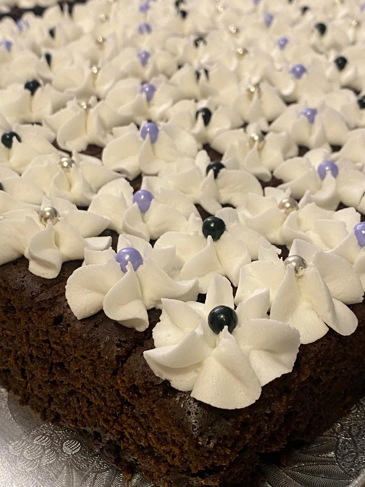 Chocolate cake with white frosting, decorative purple and black edible pearls, and silver beads on top. | Any Reason To Bake