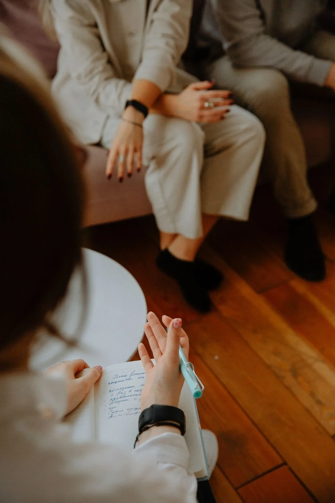 A couple sitting on a couch in front of their therapist, the psychologist is taking notes