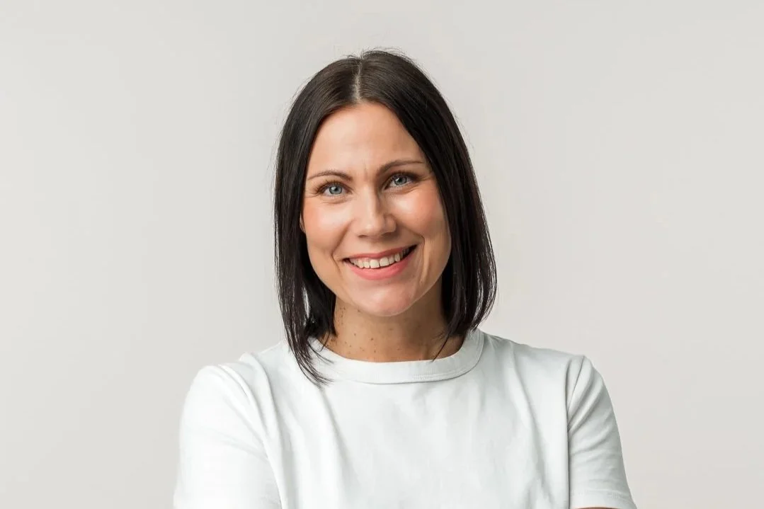 Henkilö, joka hymyilee valkoisella taustalla.