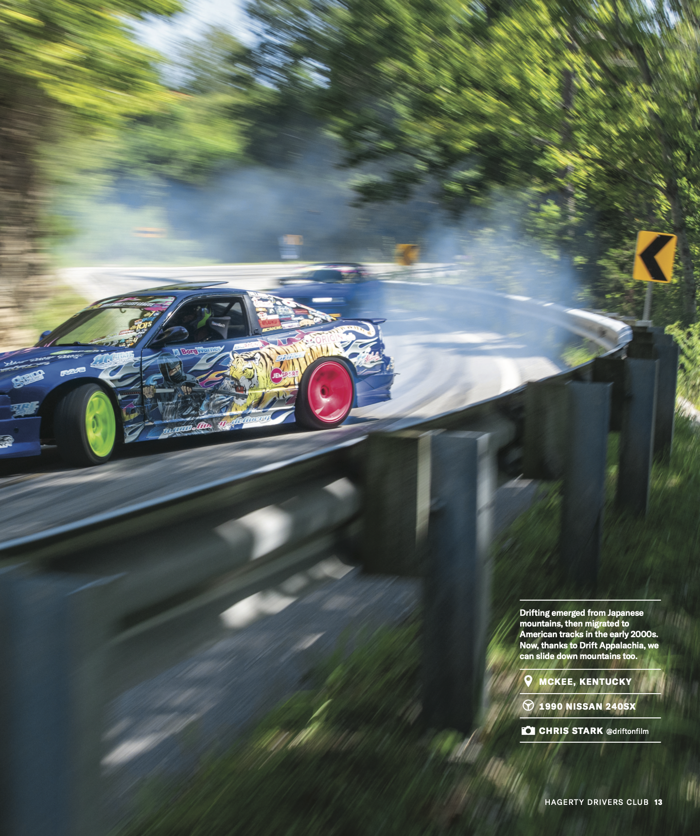 A colorful drift car with anime-style artwork on the side, drifting on a mountainous road surrounded by green trees, with smoke rising from the tires as it slides around a corner.