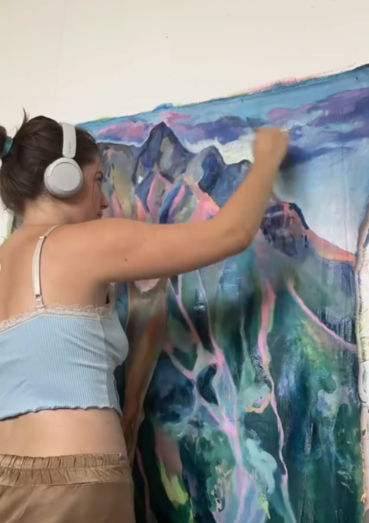 Une personne portant un casque blanc peint un tableau mural avec des couleurs vives et des formes abstraites.
