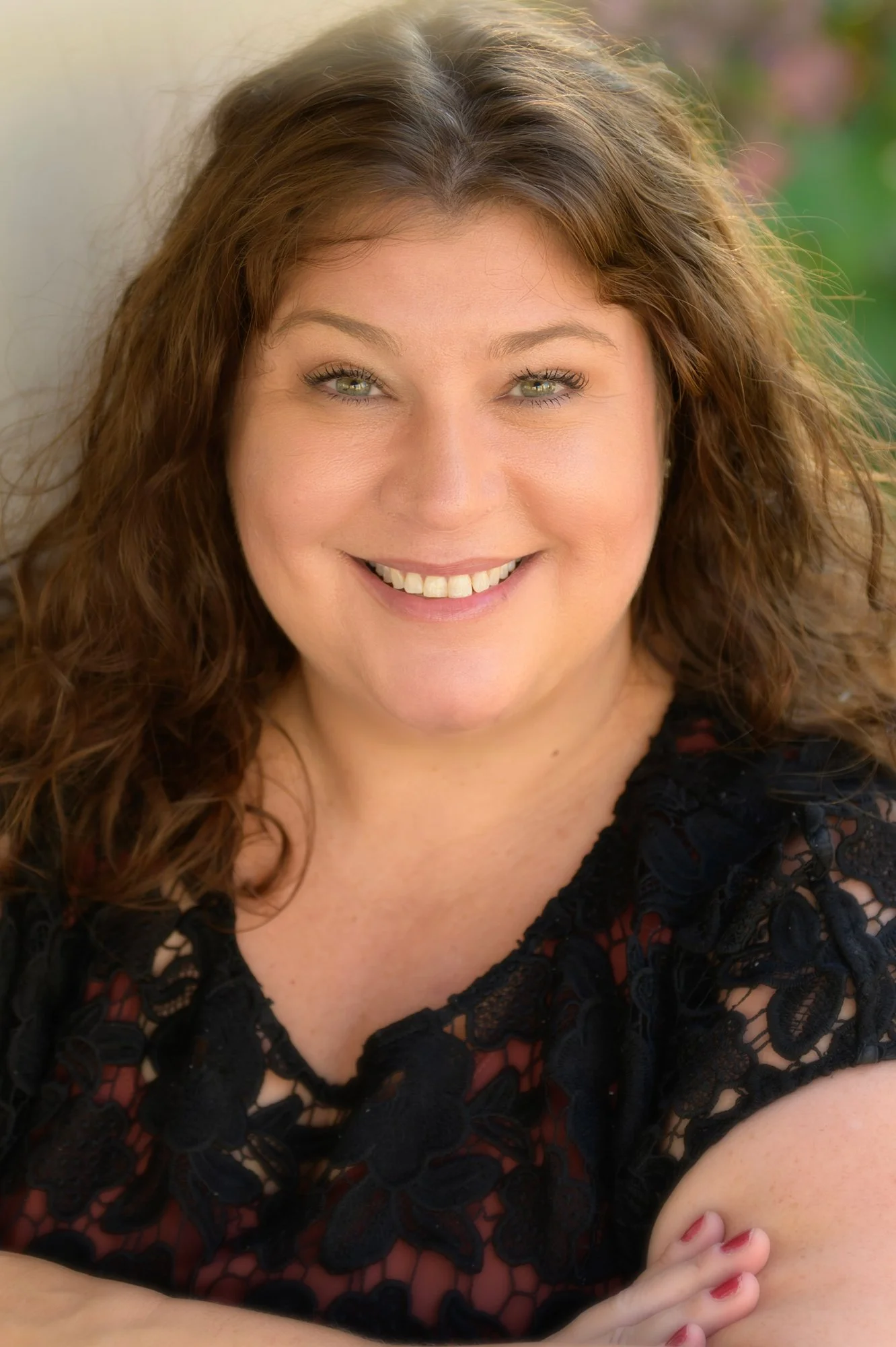 brunette woman with green eyes smiling and wearing a black lace top  