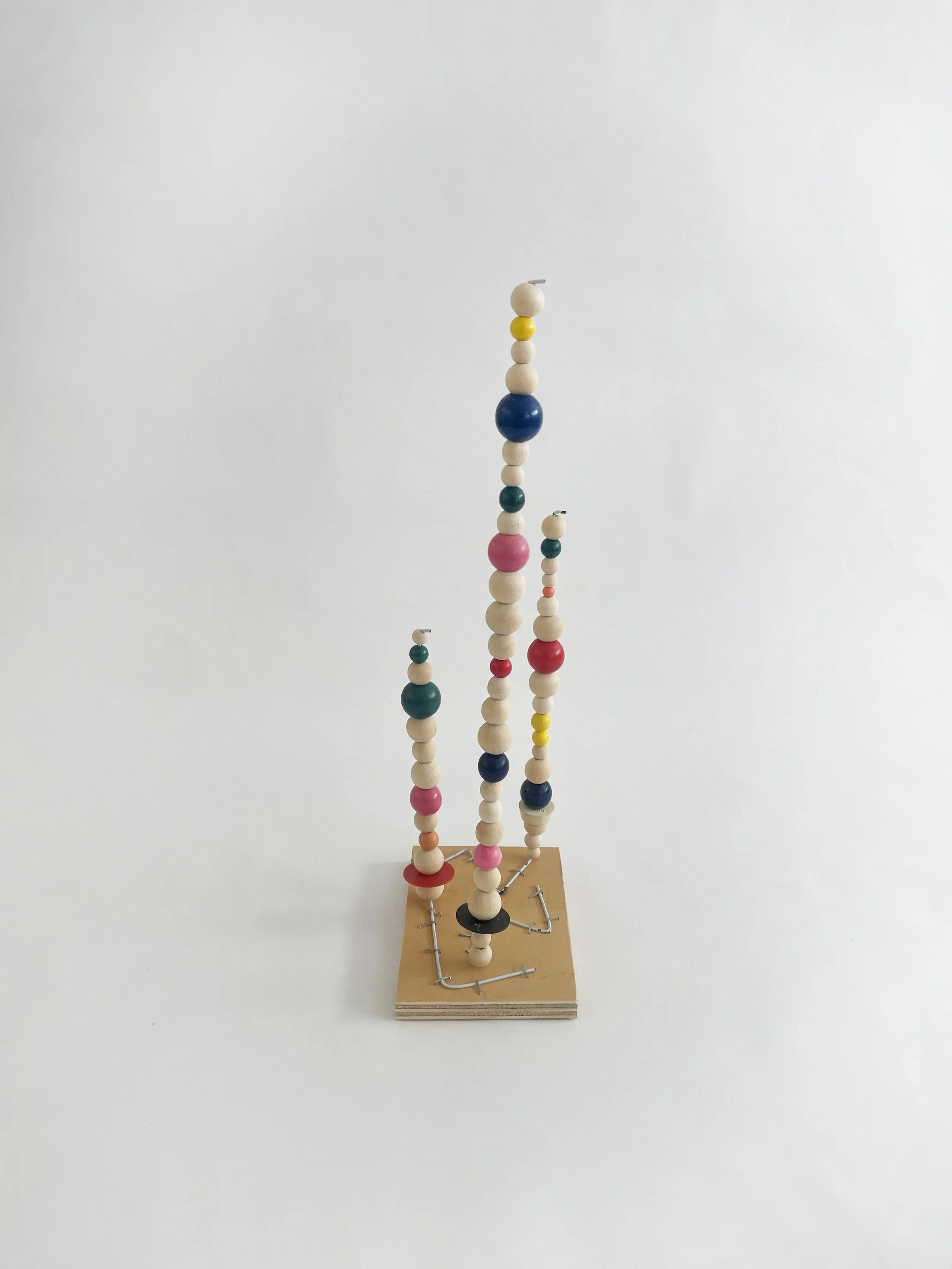 Untitled (watts tower), 2026, 16h x 6w 4d - natural and color wood beads, wire hangers, heavy duty staples, plywood, felt. 