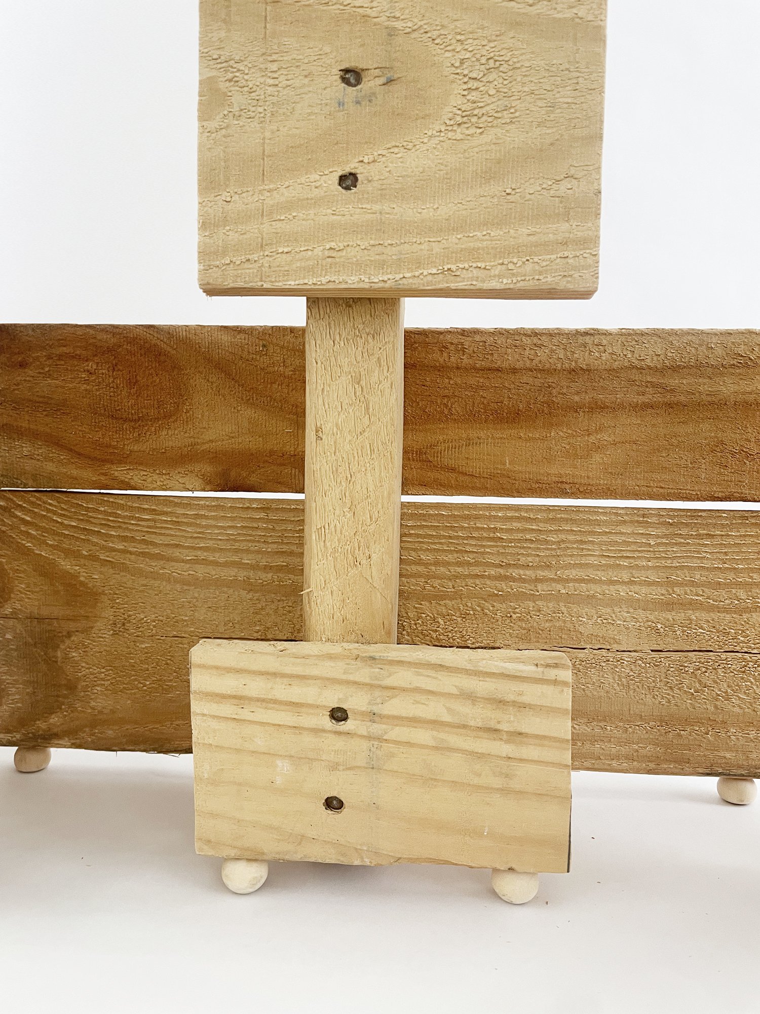Untitled (Three Graces), 2025, 37h x 32w x 11d - salvaged wood pallet, wood balls {feet}, threaded rod, epoxy, wood glue, dowels