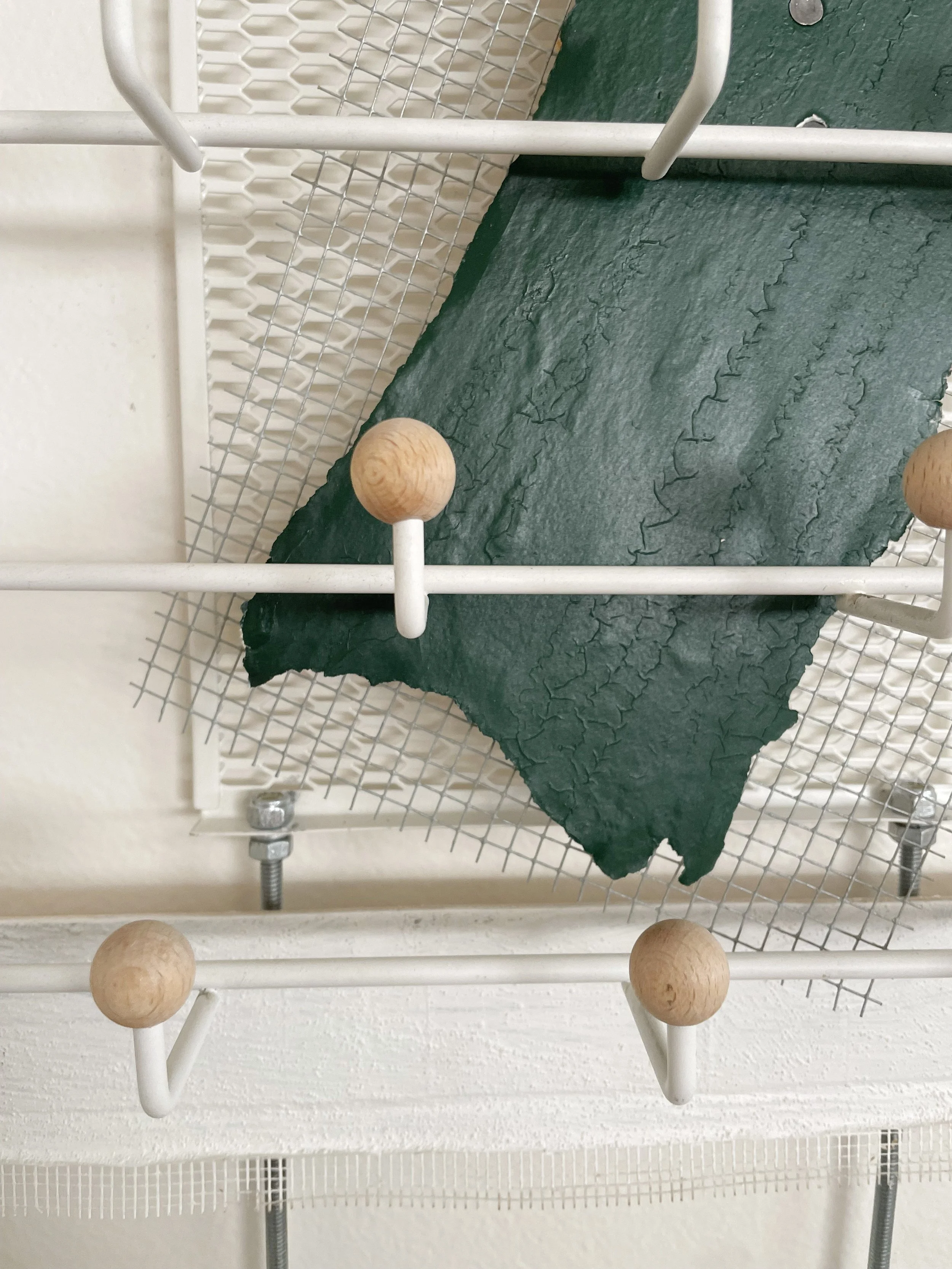 Untitled (french market), 2025-2026, 28h x 26.5w x 5d - salvaged barricade paper from the closed French Market restaurant, Ikea shelving, pre-mounted wood panel, prescription drug legal disclaimers, construction mesh, sheet rock tape, threaded rod, w