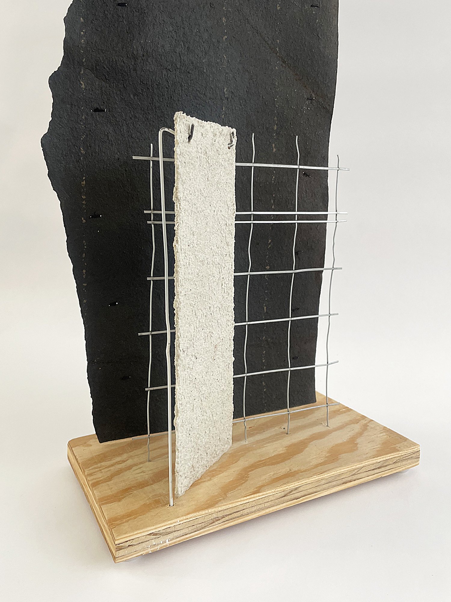 Untitled (Depeche Mode), 2025, 38h x 10w x 5.5d - salvaged plywood, black roofing paper, construction mesh, dry cleaner hanger, paper, acrylic white primer, acrylic coarse pumice gel, aluminum wire, plastic sliders {feet}, polyester thread.