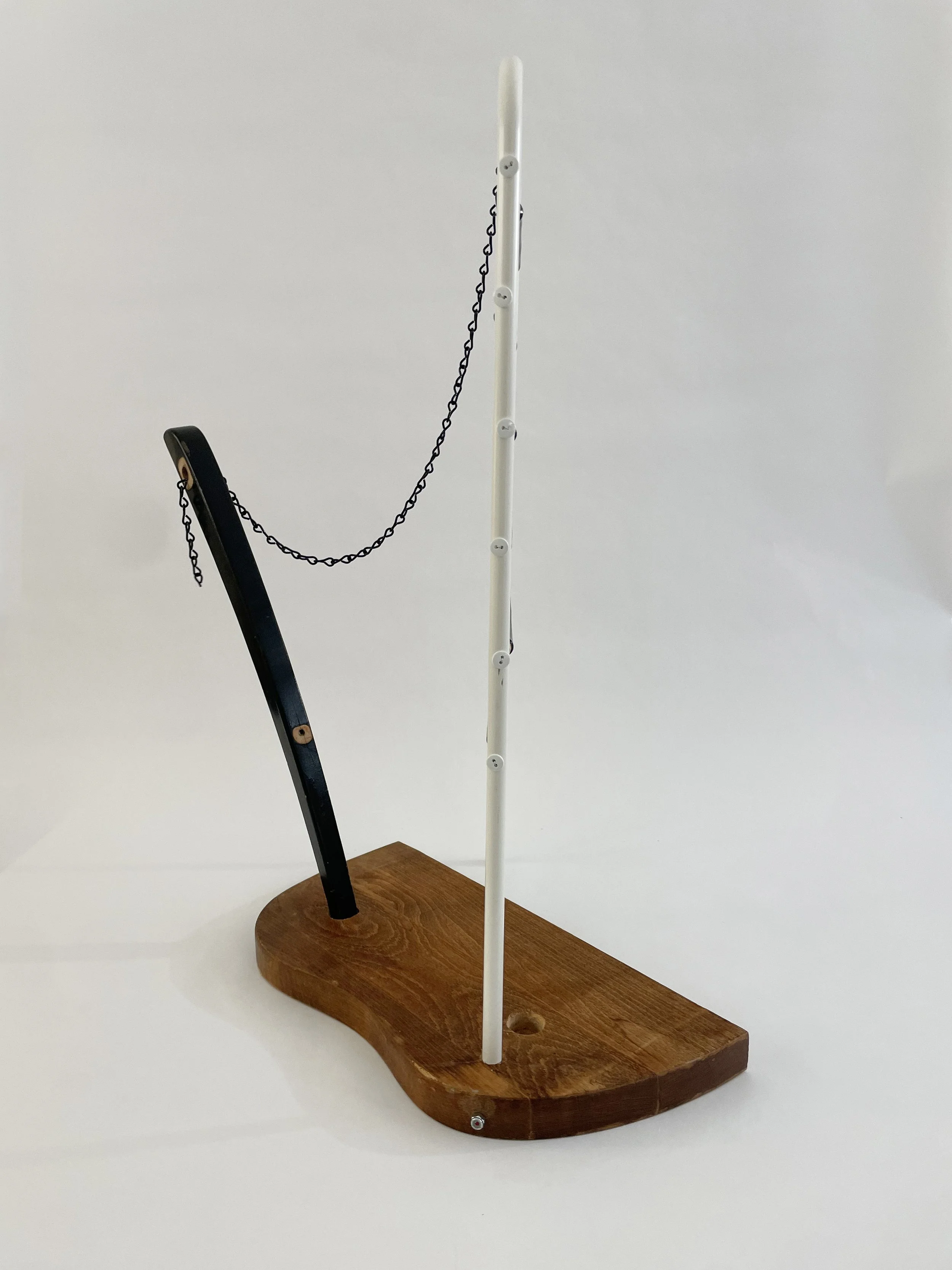 Untitled (harp), 2026, 26.5h x 21w x 13.5d - salvaged wood spindles, furniture leg, oak chair seat, Ikea aluminum legs, black zinc chain, buttons, wire, threaded rod, lock knots