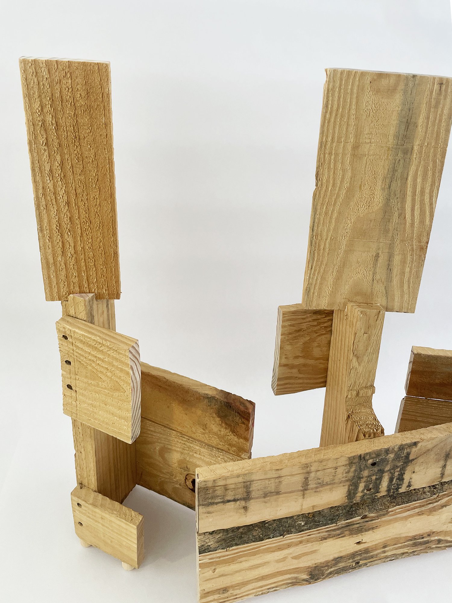 Untitled (Three Graces), 2025, 37h x 32w x 11d - salvaged wood pallet, wood balls {feet}, threaded rod, epoxy, wood glue, dowels