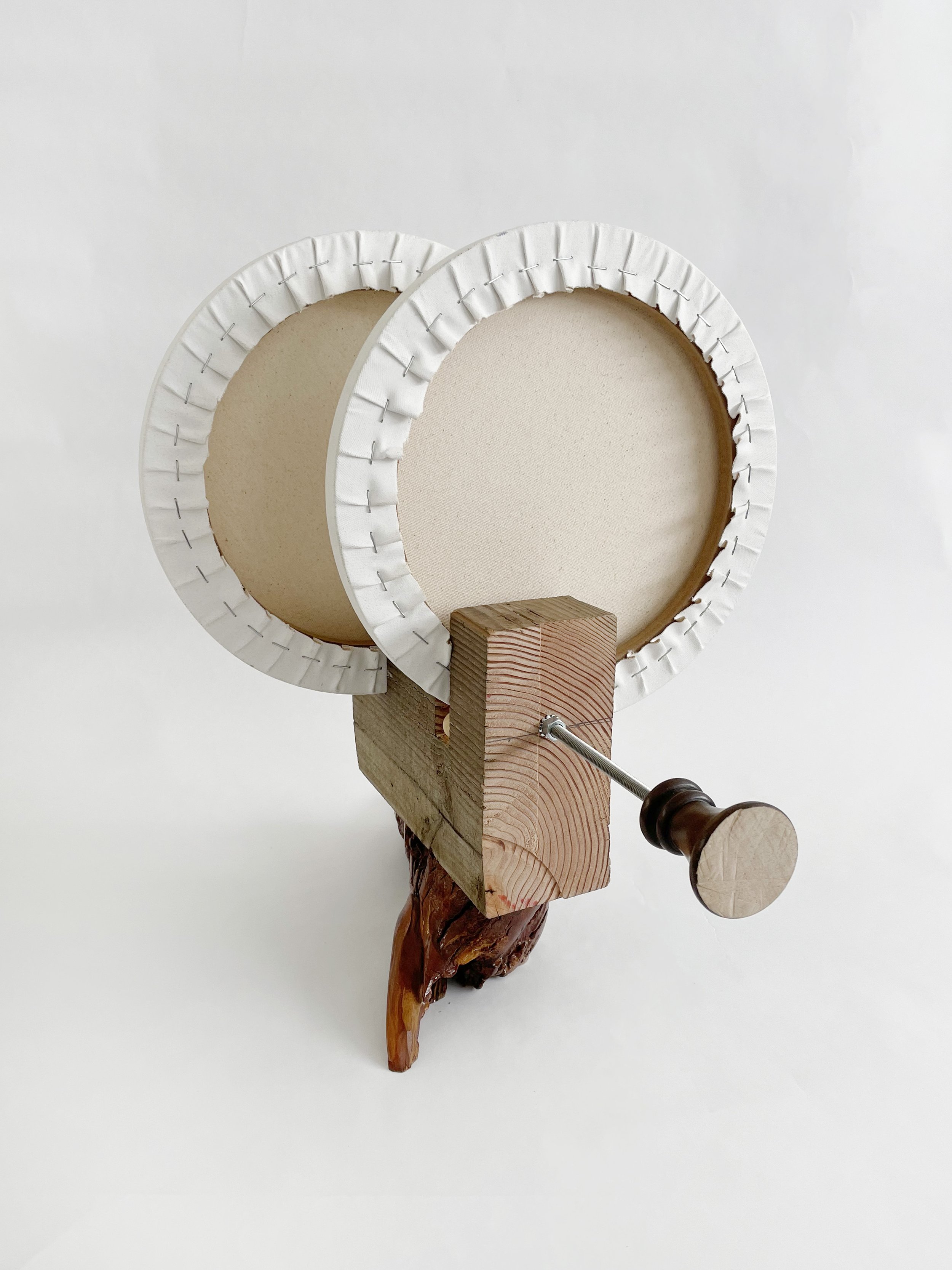 Untitled (two disks) 2025- 2026, 19.5h x 16w x 22d - thrift store resin coated driftwood, 3x7 construction timber, threaded rods, lock nuts, 2 pre-primed round stretched canvas, wood finials, dowels, wood beads.