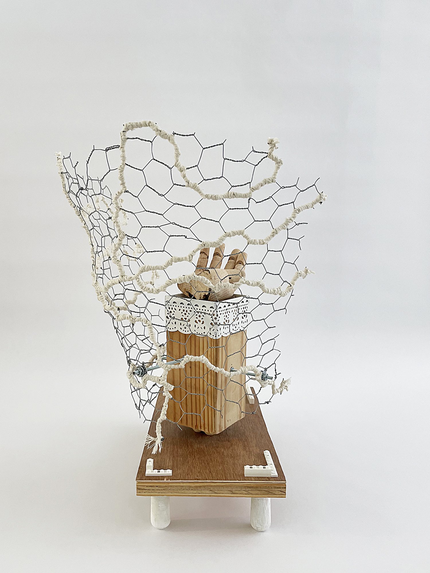 Untitled (Logan's Clock), 2025, 19h x 14w x 14d - salvaged plywood,4x4 lumber, walnut veneer, wood pegs {feet}, Ikea wooden model hand, chicken wire, butcher's string, Ikea metal trim, cotton fabric, threaded metal rod, wood beads, nuts, washers,